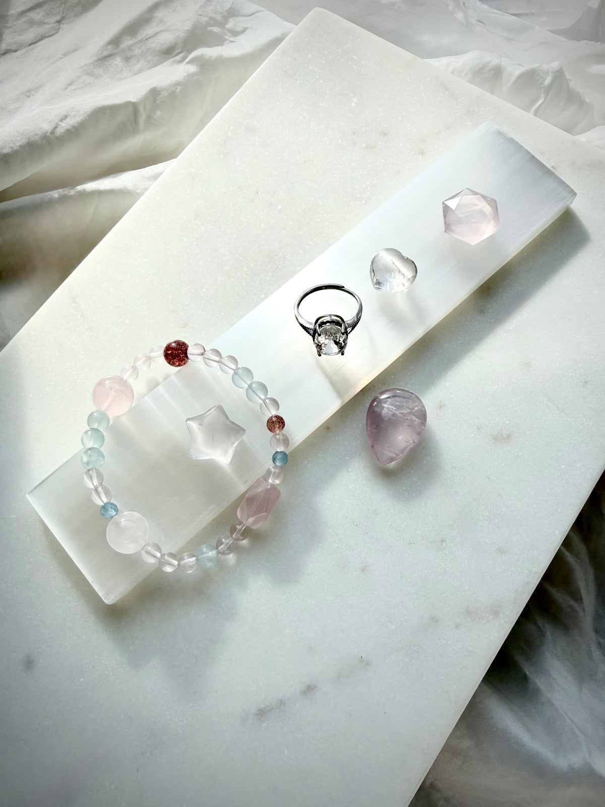 White Selenite charging wand displayed with small crystals and jewelry for crystal cleansing, charging and energy purification rituals