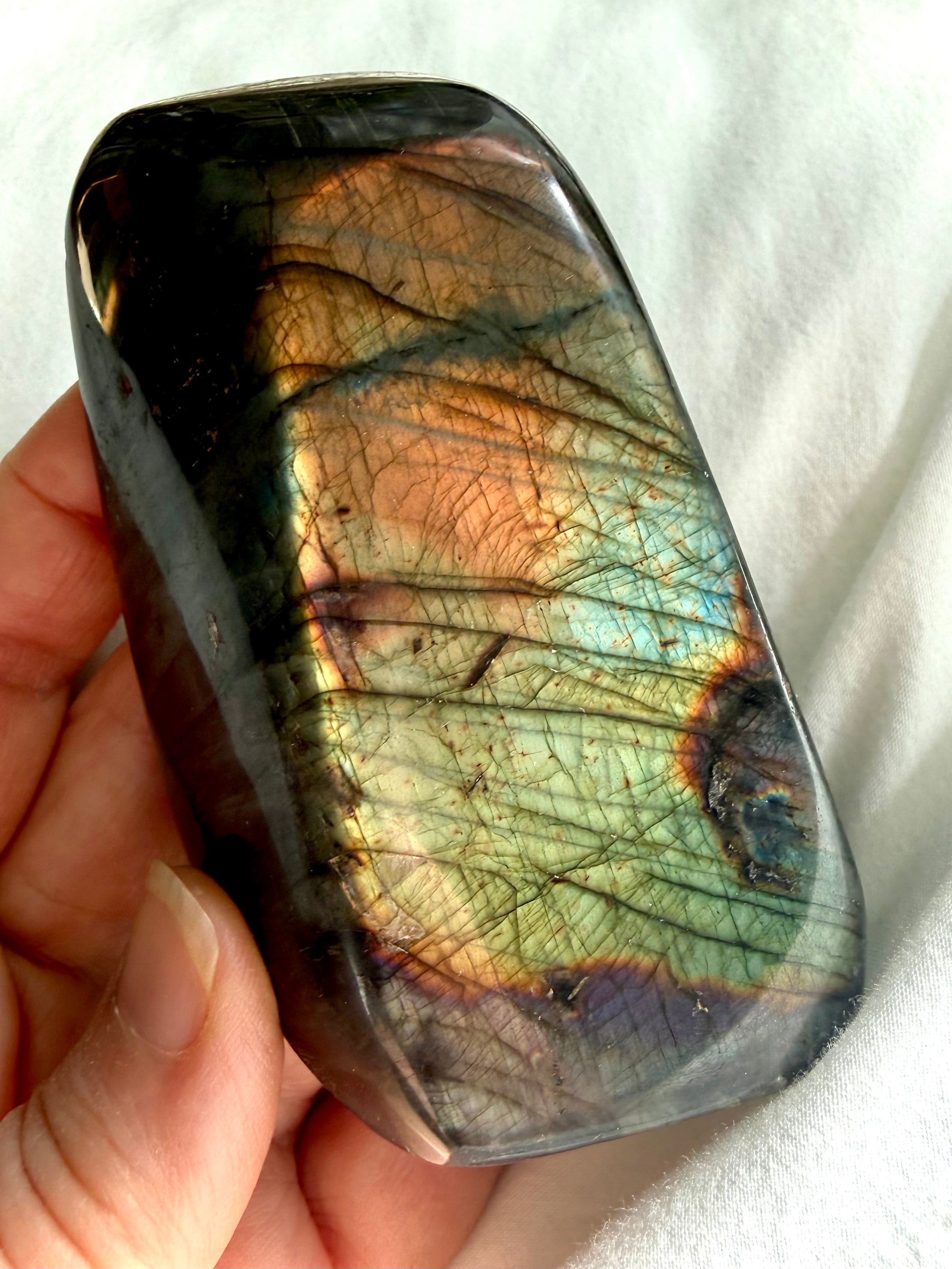 Reverse side of Labradorite freeform with softer green, aqua, gold, and copper flash across the dark polished stone