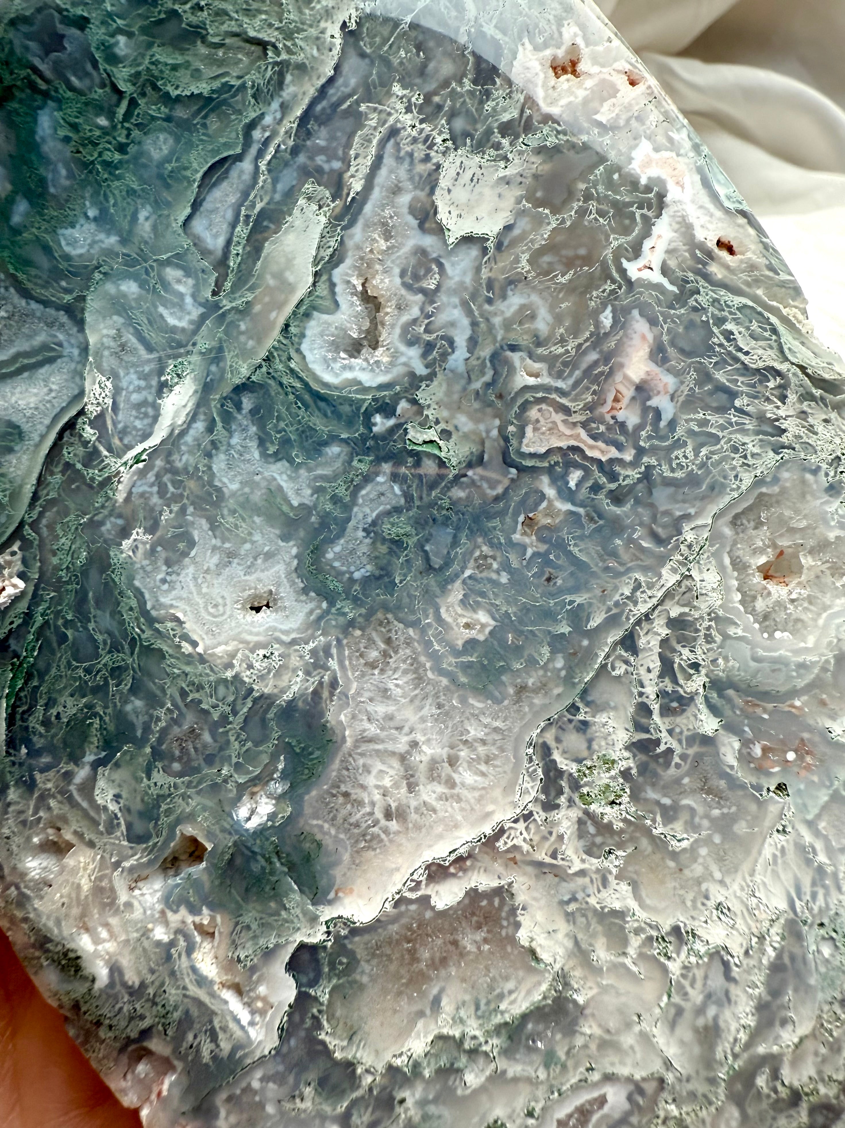 Close-up detail of moss agate flame carving with lacy agate, druzy quartz and luminous teal tones