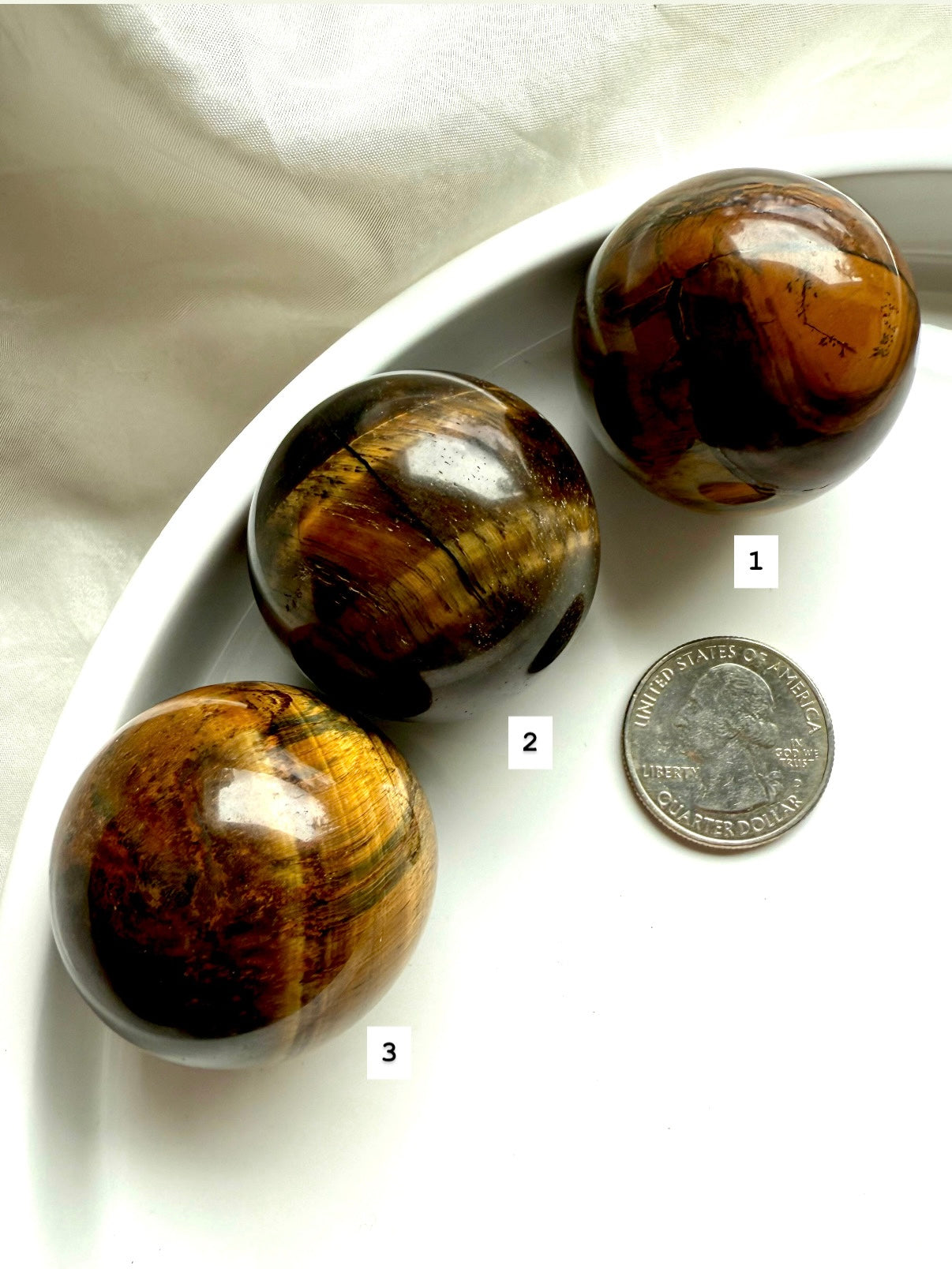 Three Tiger’s Eye spheres with a quarter for scale — grounding crystals for protection and clarity