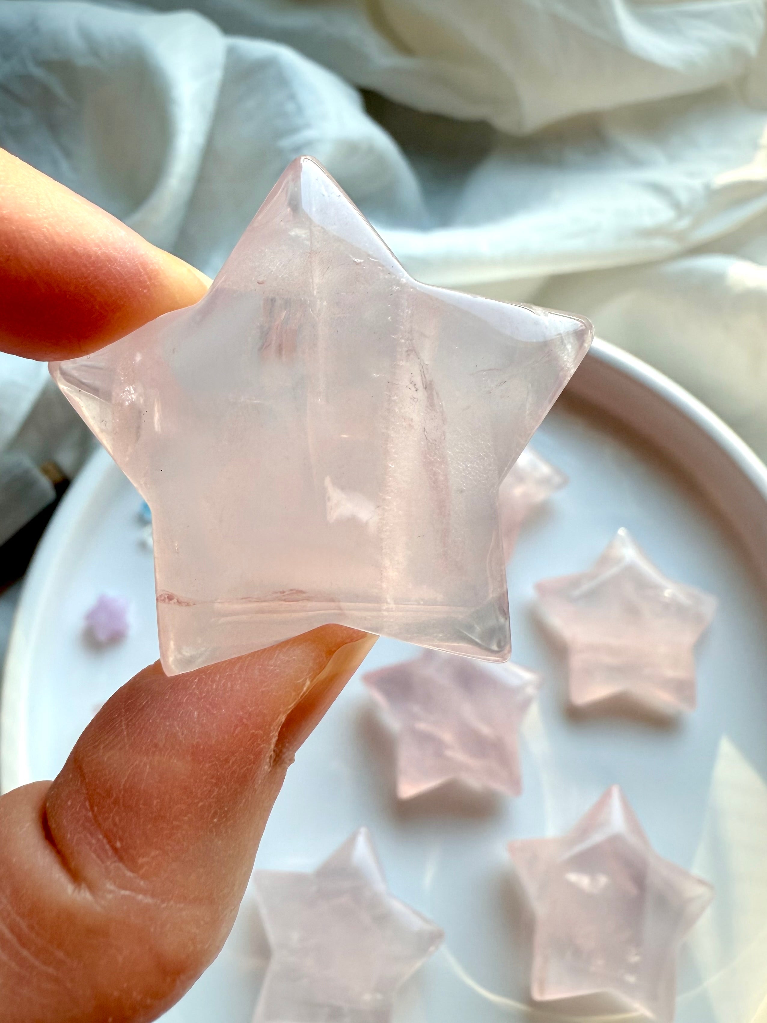 Rose Quartz star carving in hand showing natural variation and soft pink clarity — large Mozambique Rose Quartz star for love and heart chakra energy.