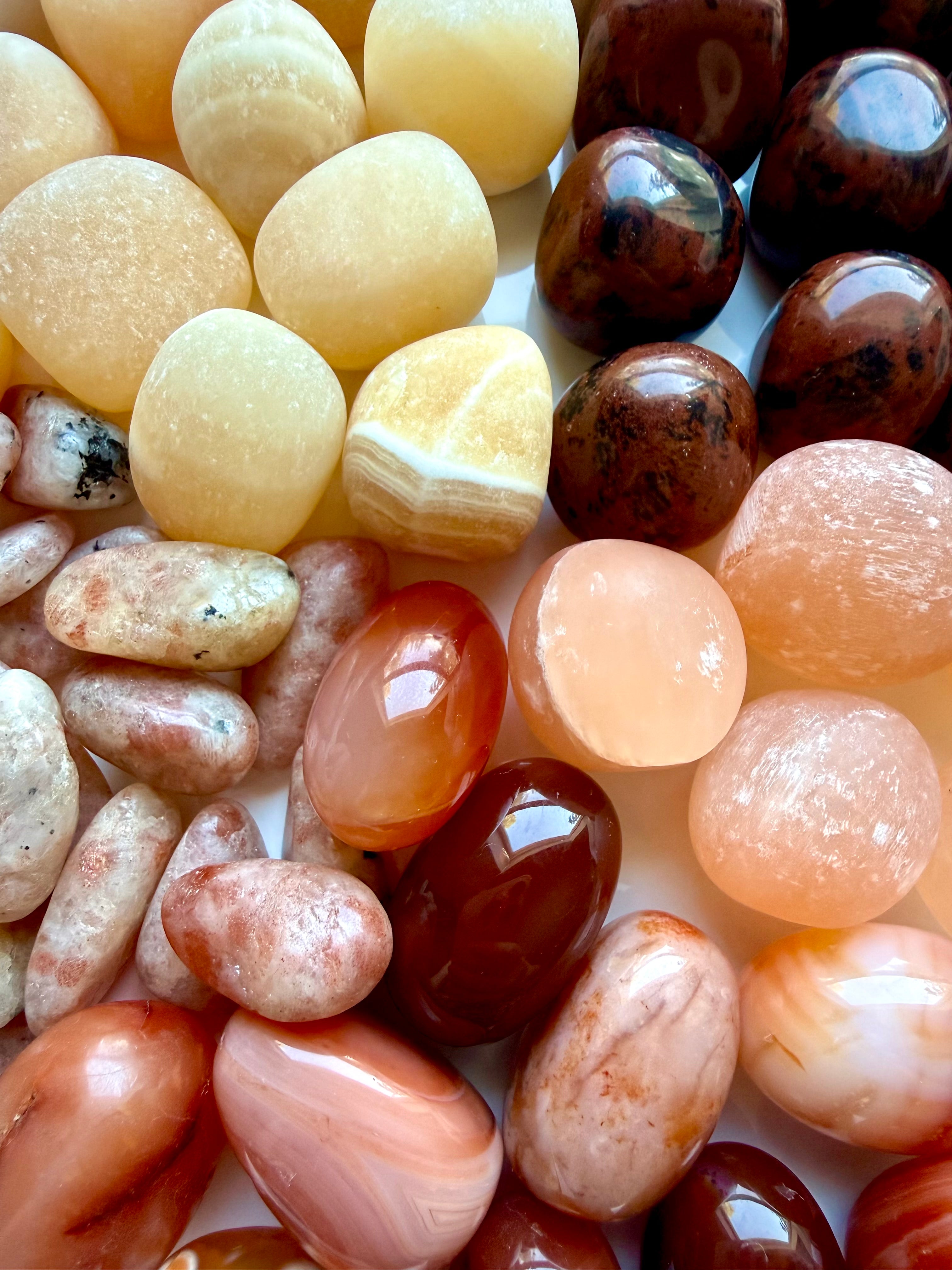 Close-up of polished Sacral Chakra stones in orange, peach, cream, and deep red with natural color and pattern variation