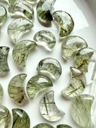 Green Tourmaline Quartz moon carving held in hand, a Heart Chakra crystal associated with growth, abundance and renewal