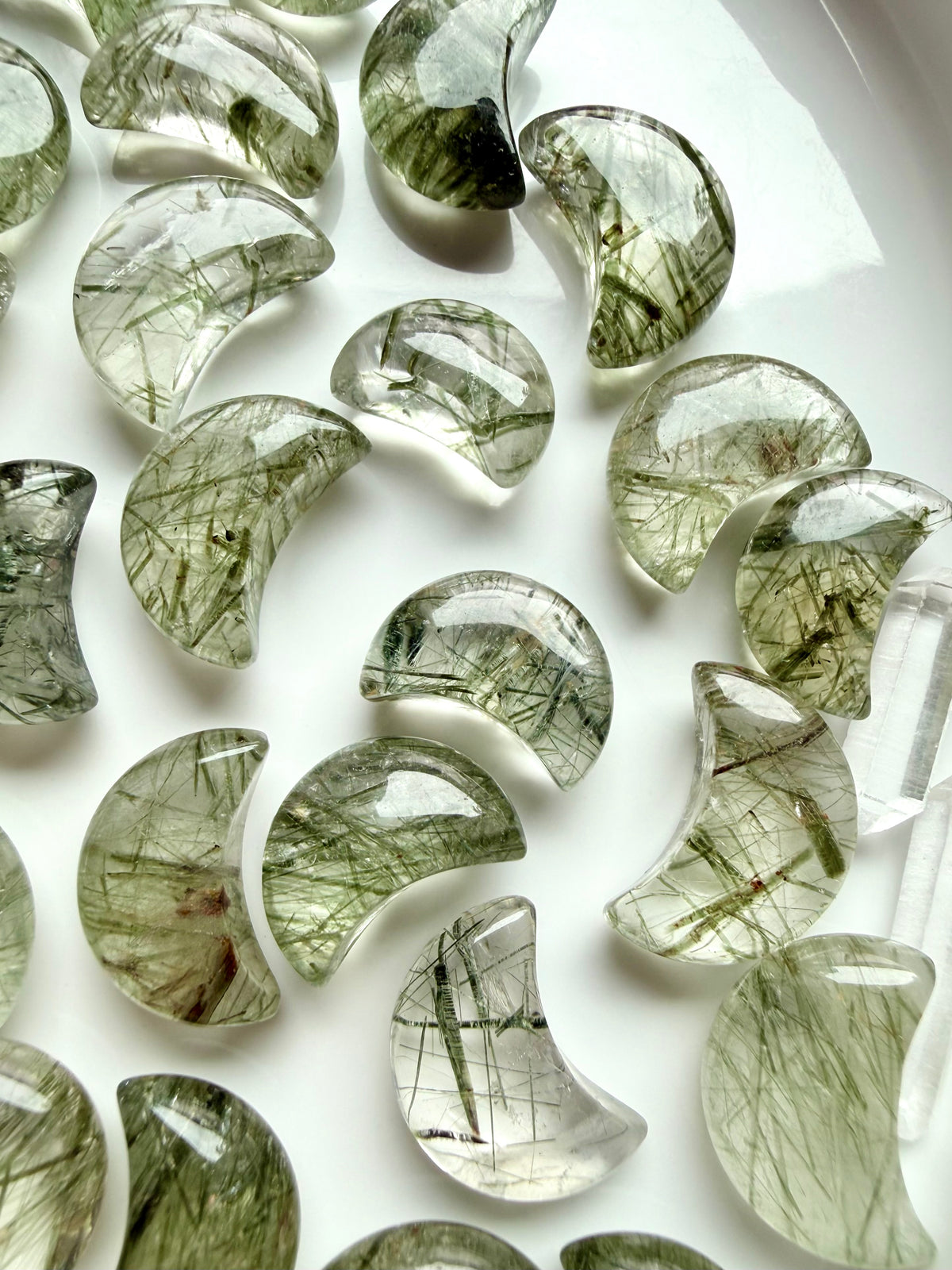 Green Tourmaline Quartz moon carving held in hand, a Heart Chakra crystal associated with growth, abundance and renewal