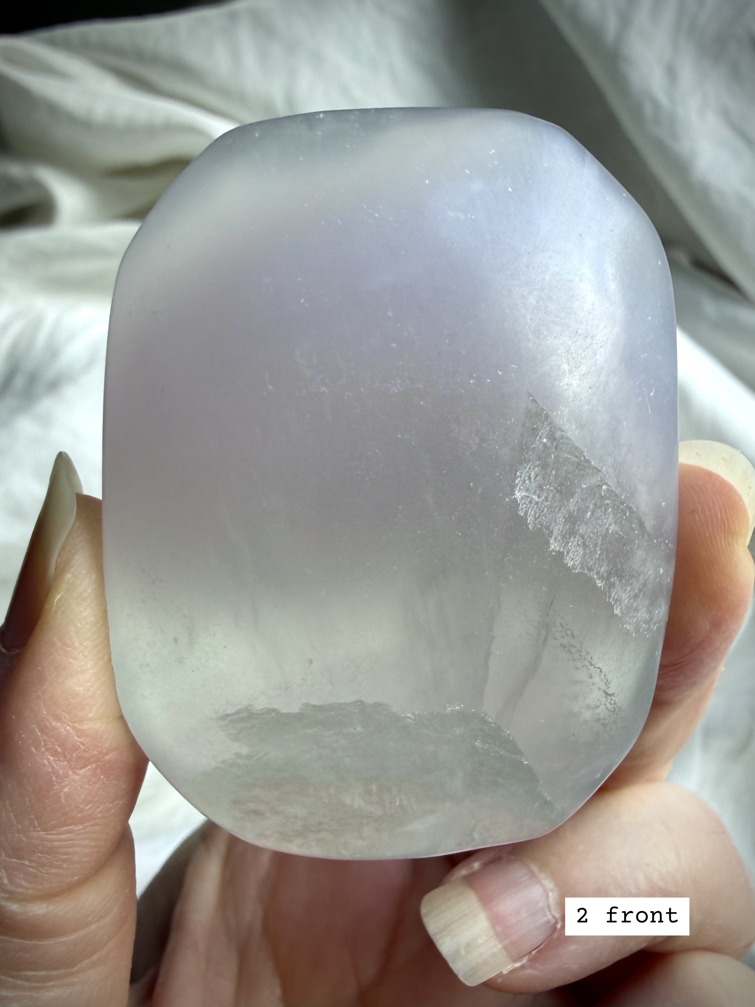 yttrium fluorite palm stone #2 front view with smooth polish and subtle banding in soft pastel tones
