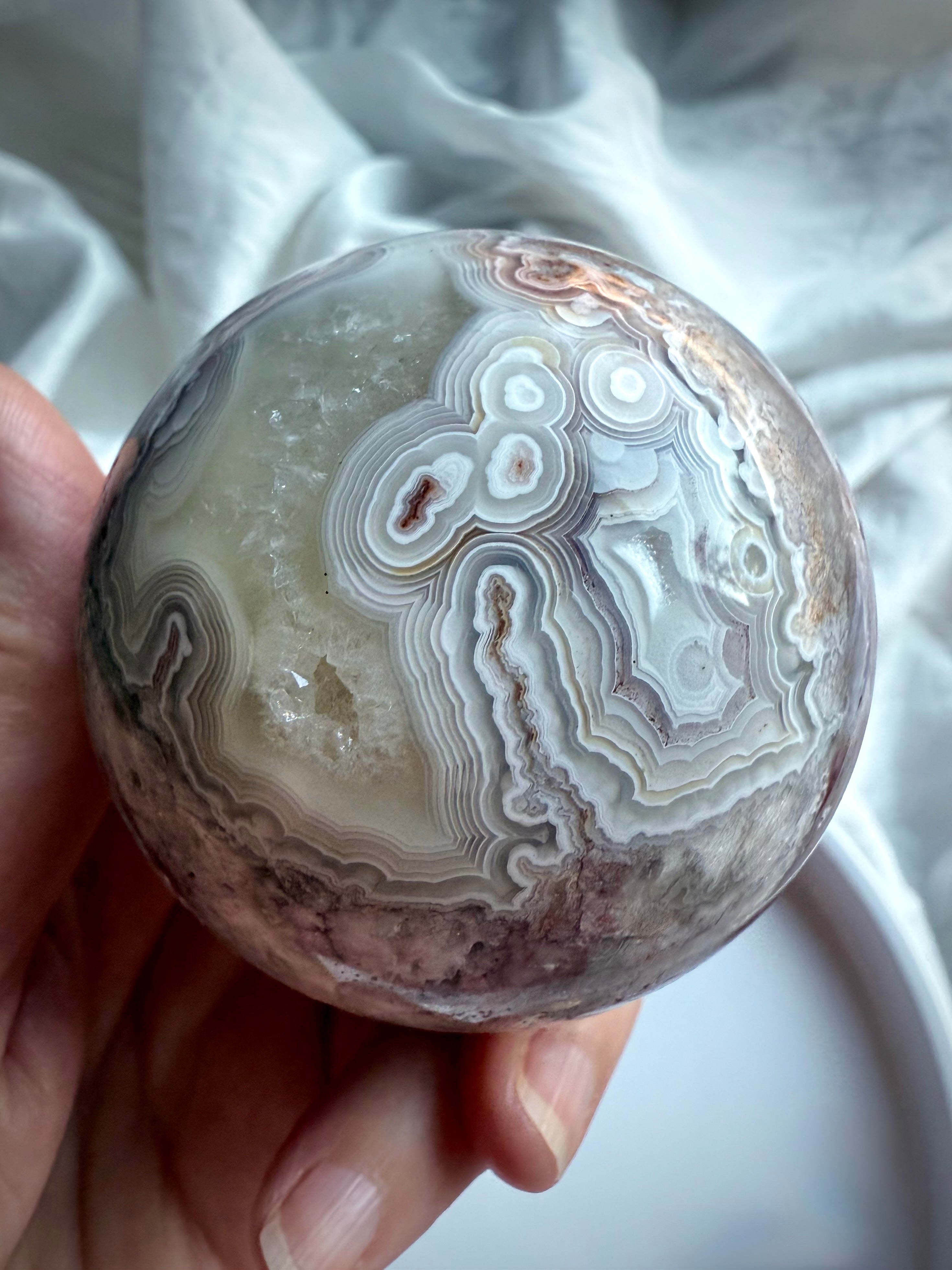 Orbicular Crazy Lace Agate sphere with layered concentric patterns and earthy tones of plum, beige, and charcoal