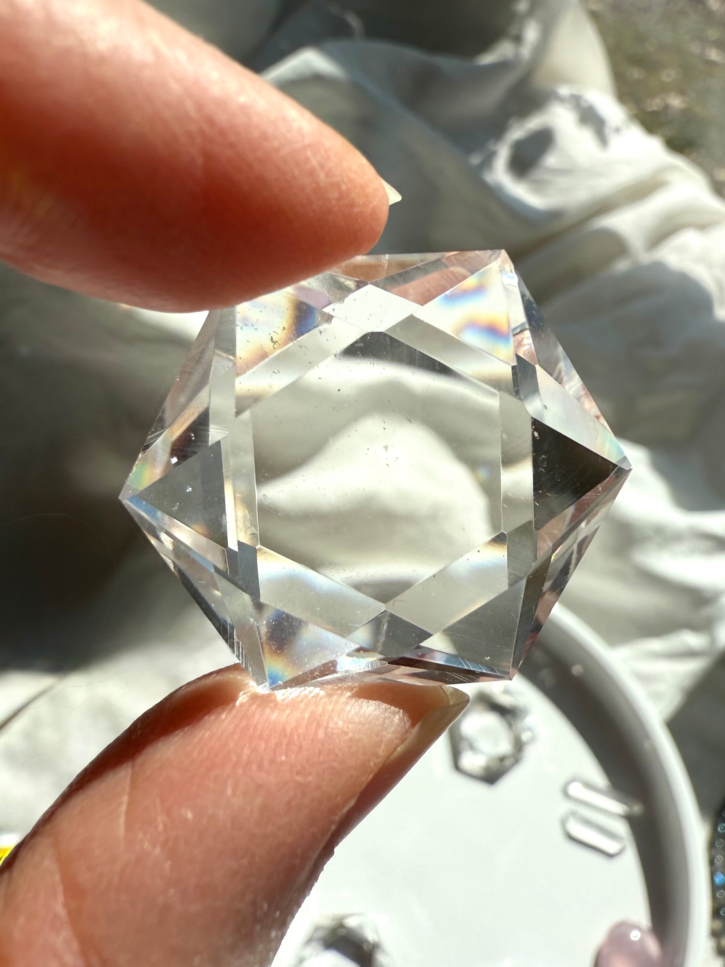 Closeup of faceted Clear Quartz hexagon held to the light, showing water-clear transparency and gemmy polish