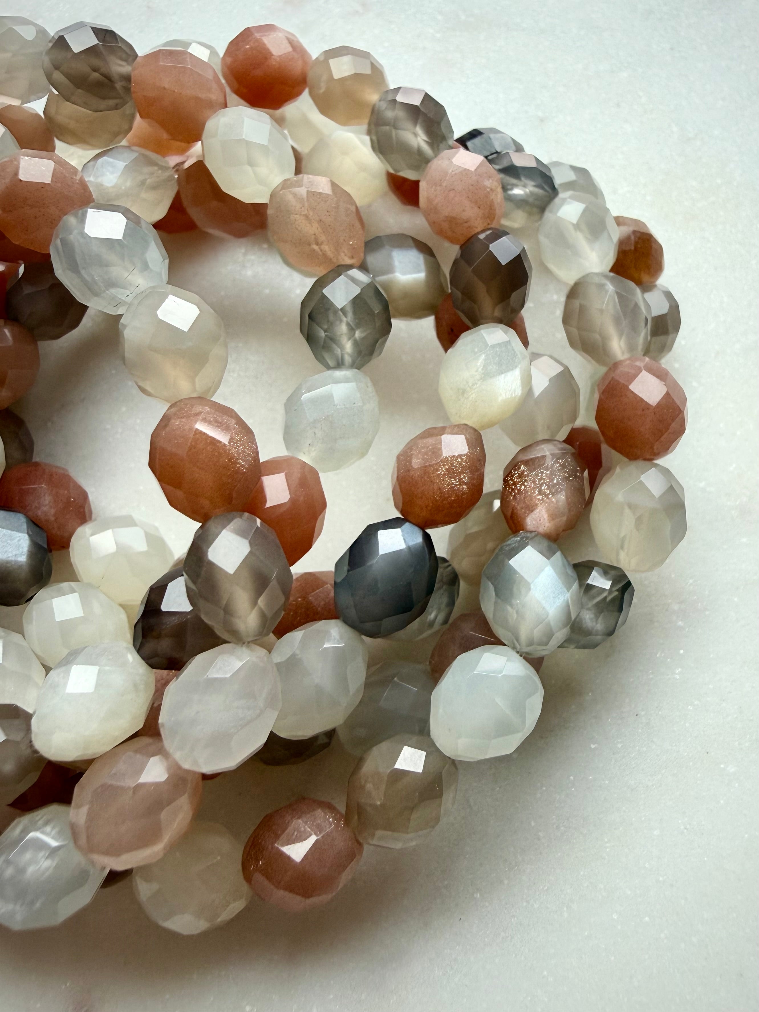 Faceted Moonstone crystal bracelets arranged together, displaying translucent gemstones and contrasting warm and cool tones