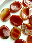 Polished oval Carnelian worry stones arranged together showing unique Agate banding, translucency and natural patterns