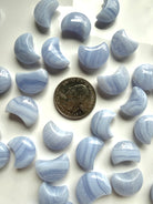 Blue Lace Agate crescent moon carvings beside a U.S. quarter for size comparison