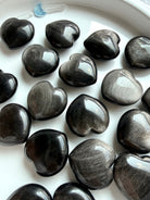 Polished Obsidian heart crystals showing variations from deep black to silvery charcoal sheen