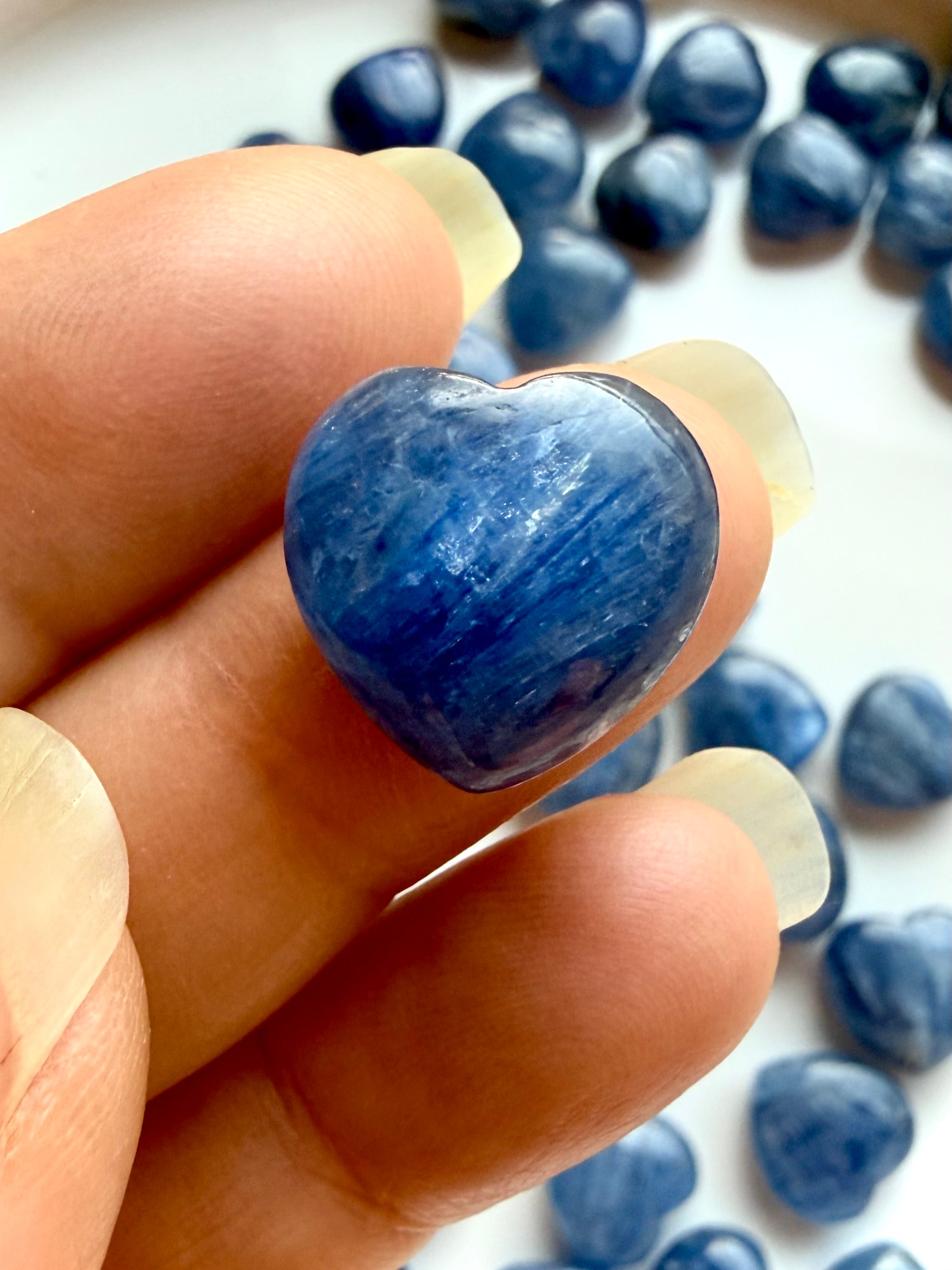 Close up of mini Blue Kyanite heart crystal with luminous cobalt blue striations and natural quartz matrix, polished on both sides