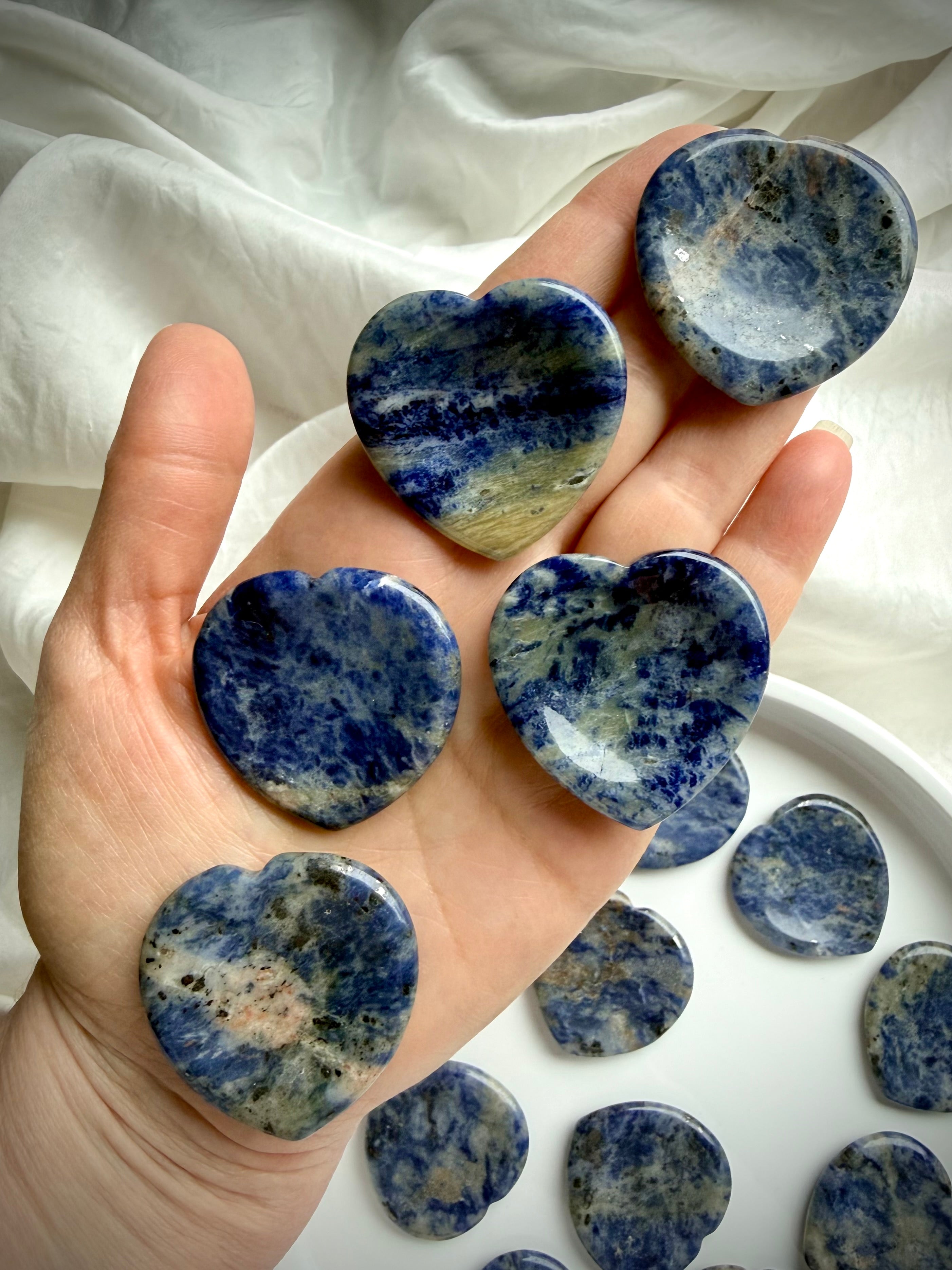 Sodalite heart worry stones in hand – blue crystal thumb stones for throat chakra clarity
