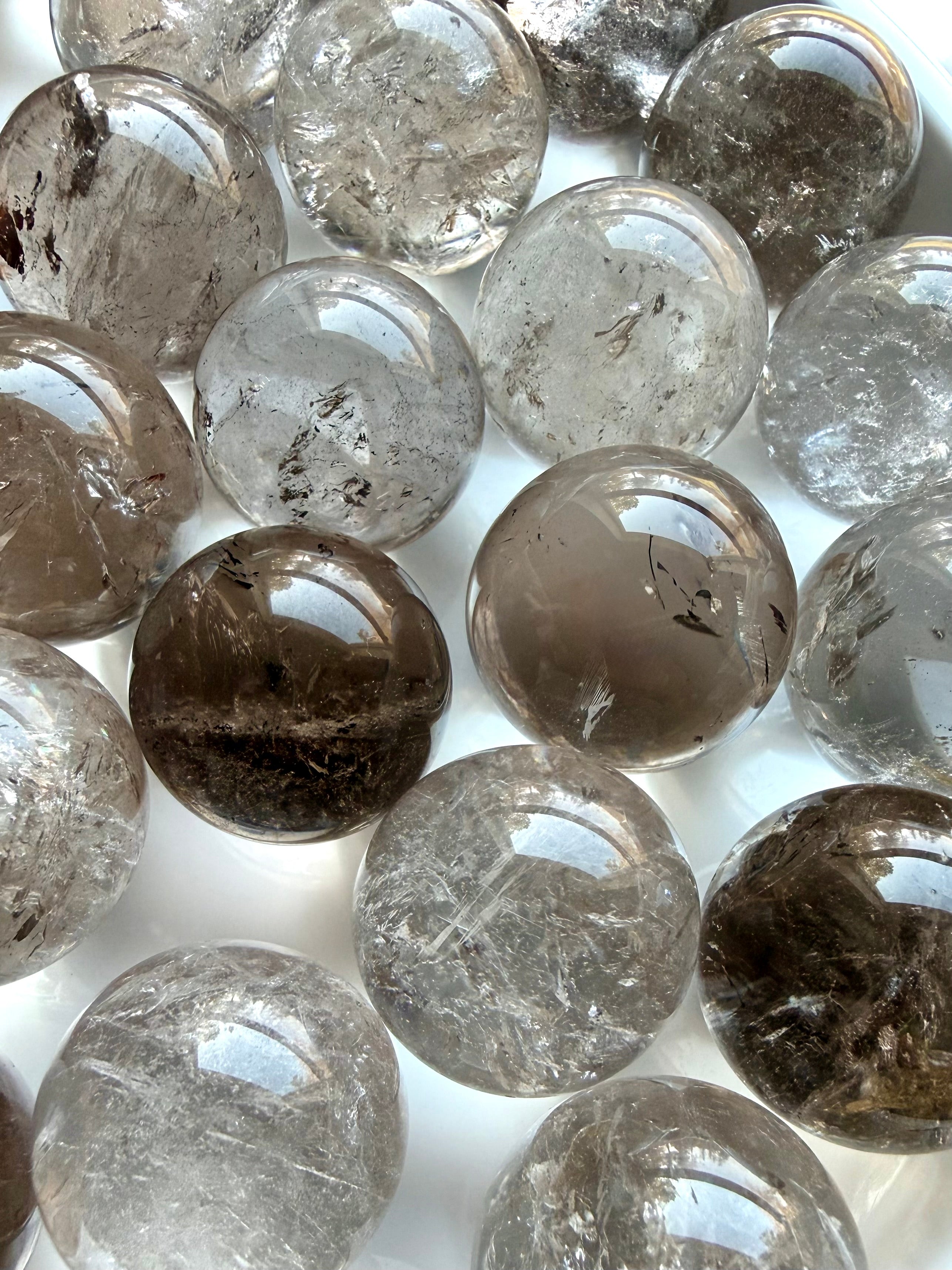 Array of mini Smoky Quartz crystal spheres close up showing color variation and internal patterns