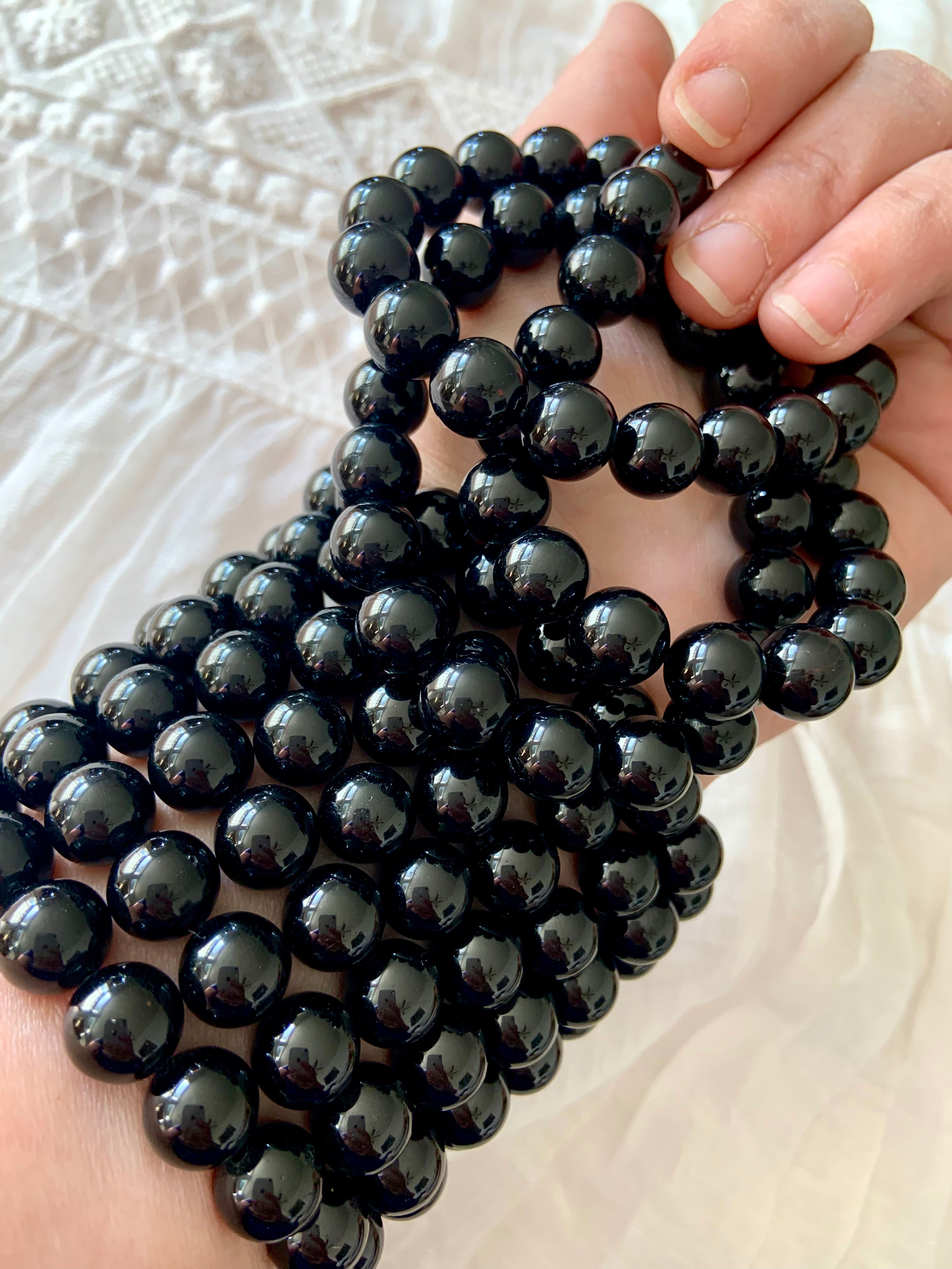 Stack of glossy Black Tourmaline bracelets worn on wrist — high quality crystal beads for grounding and energetic protection