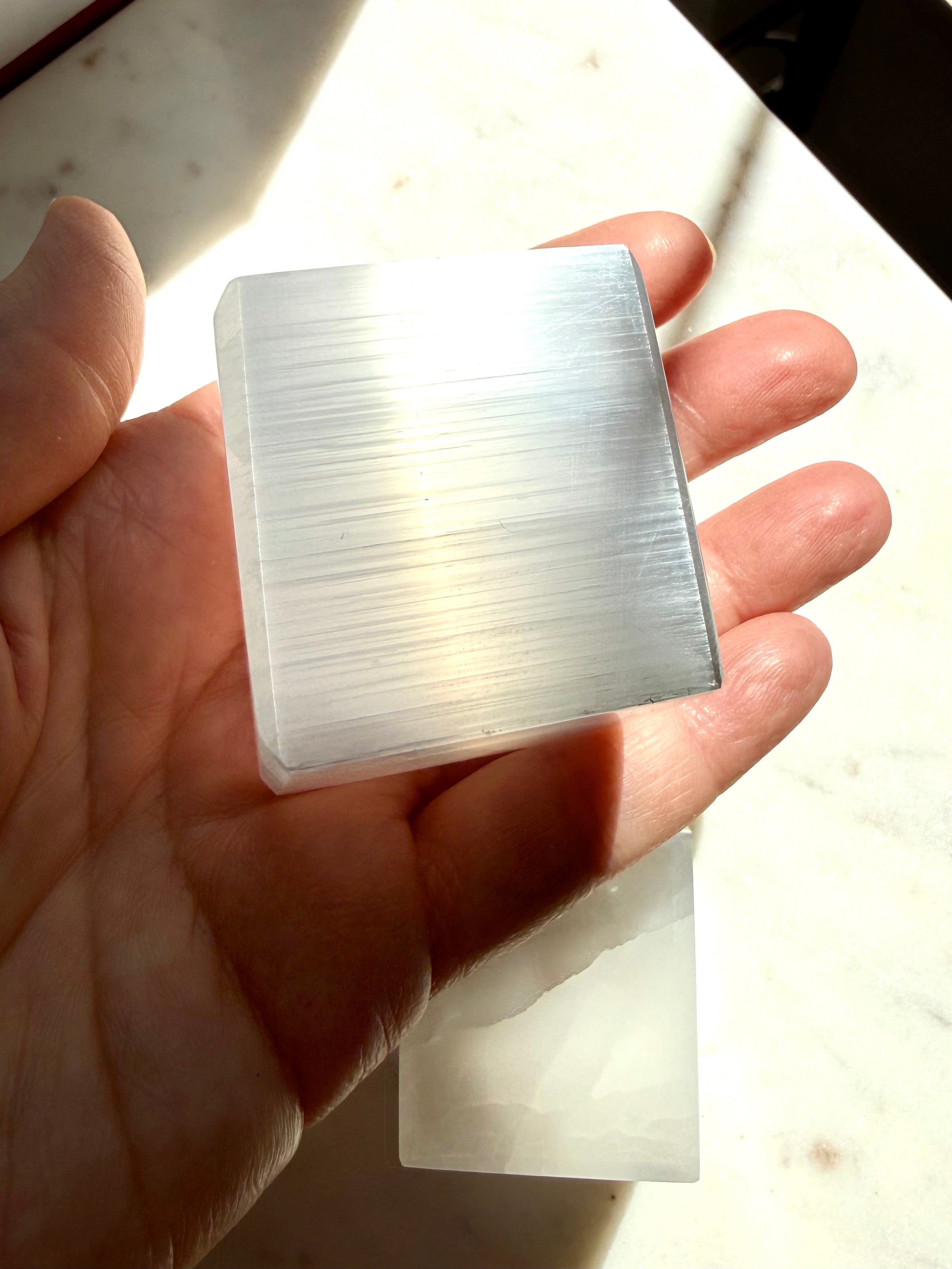 Selenite cube held in hand showing silky white crystal layers and natural satin spar sheen