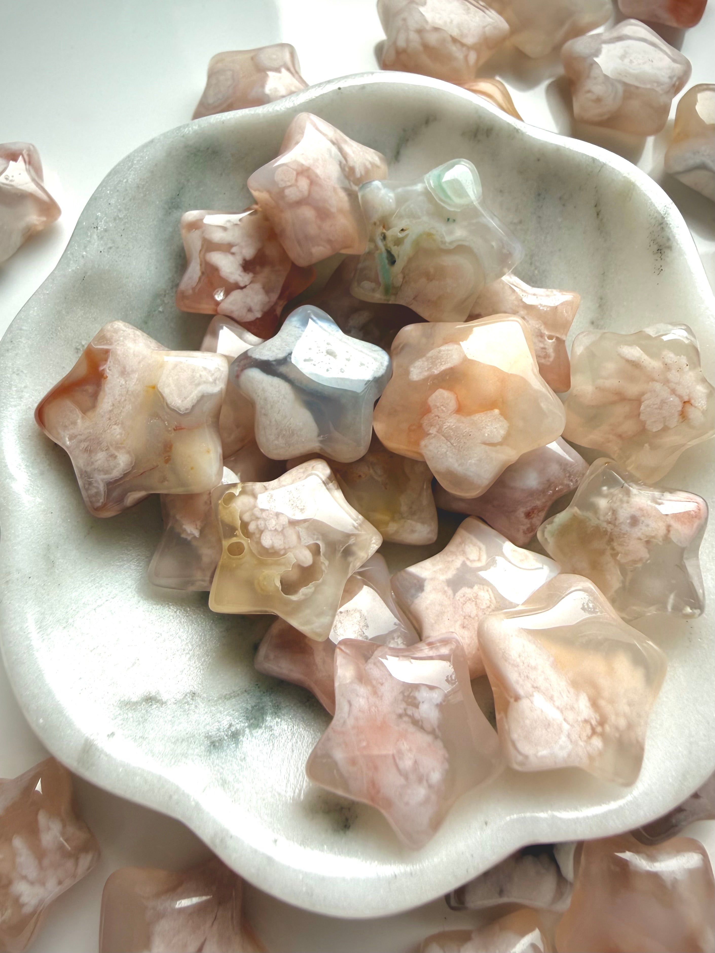 Flower Agate crystal star carvings arranged in a ceramic bowl with soft feminine pastel coloring