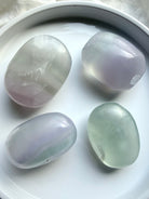 yttrium fluorite palm stones grouped together on white background showing variation in shape and color