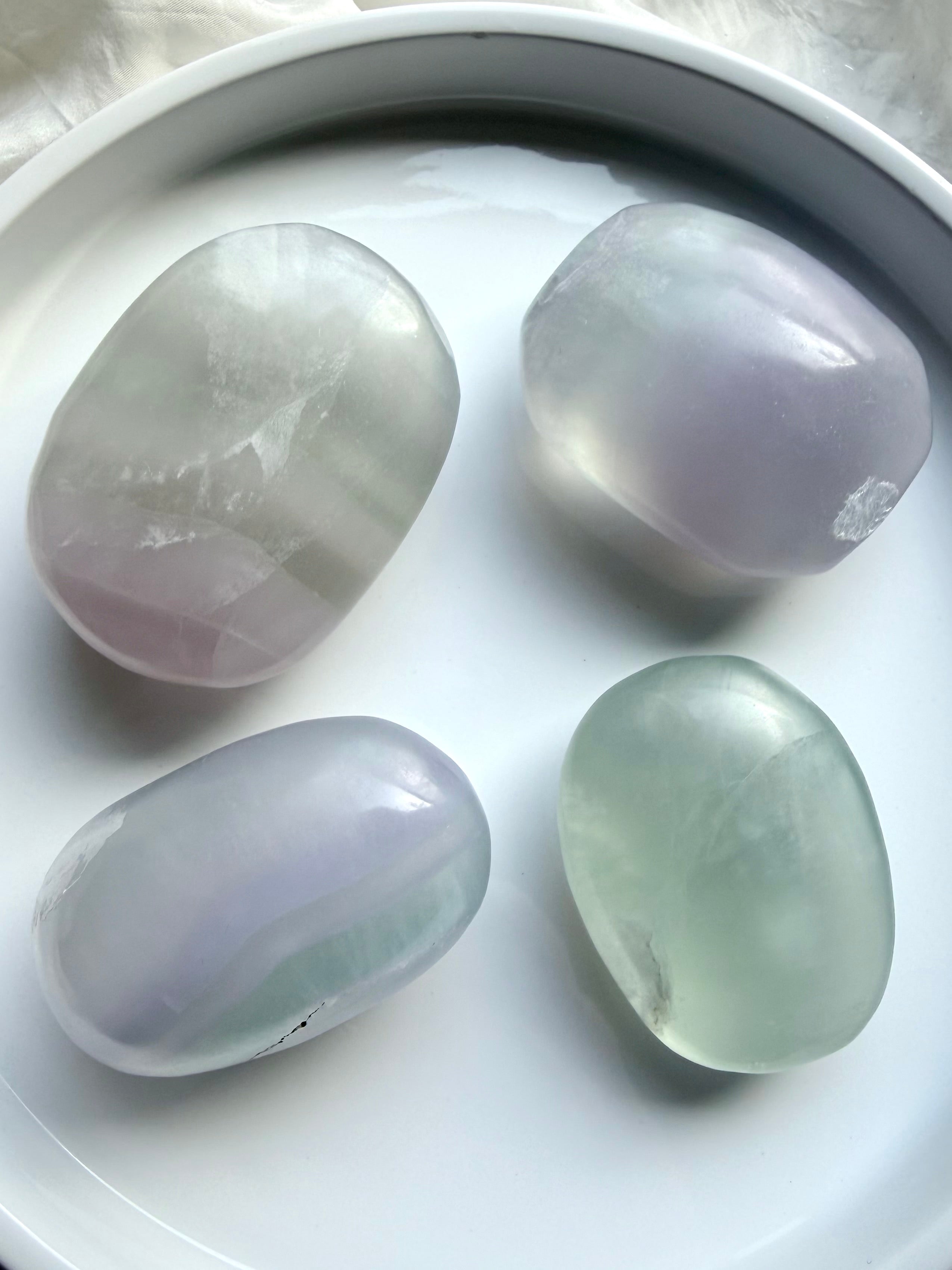 yttrium fluorite palm stones grouped together on white background showing variation in shape and color