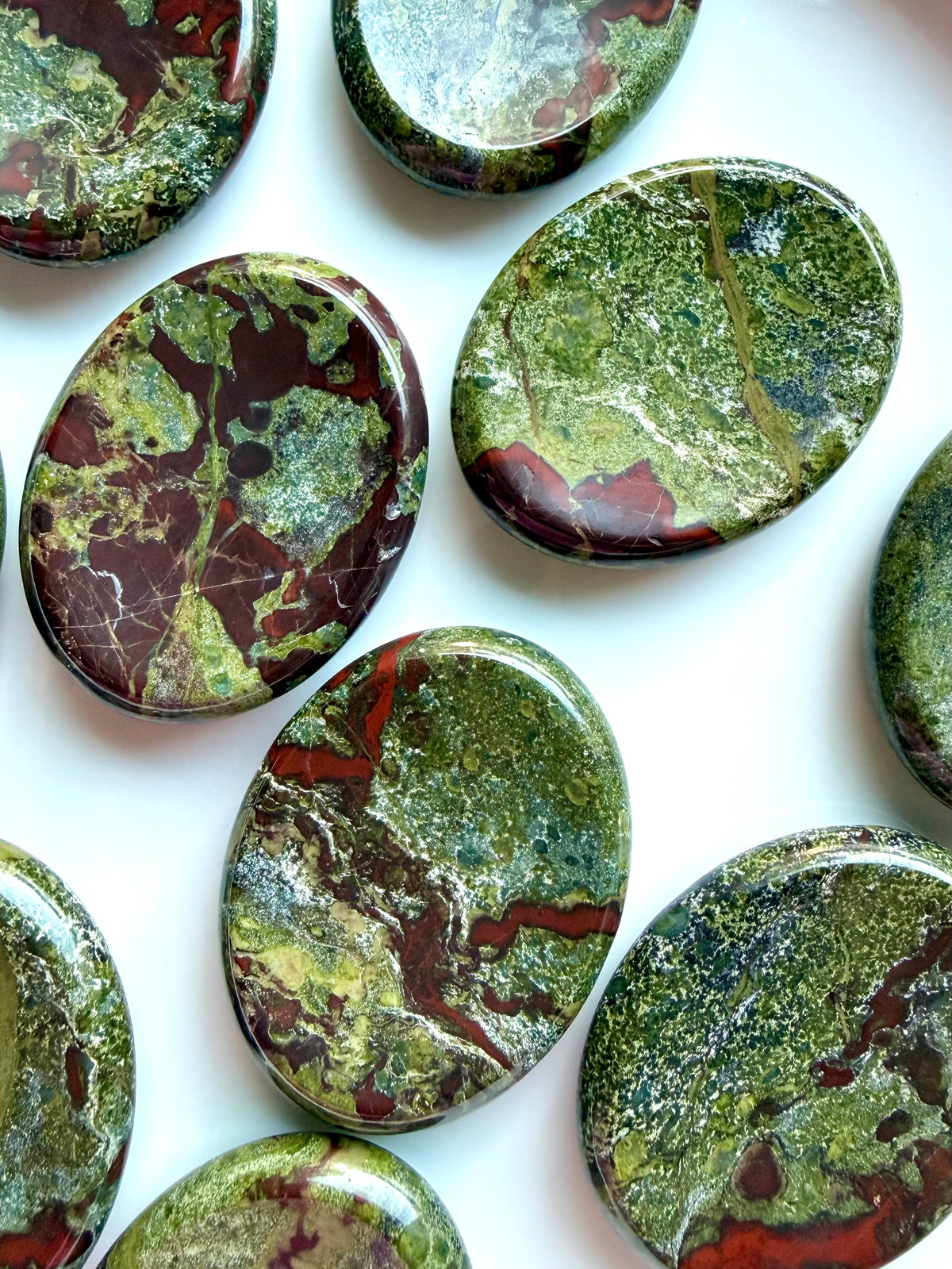 Collection of Dragon Blood Stone worry stones with earthy green and burgundy coloring for meditation and stress relief