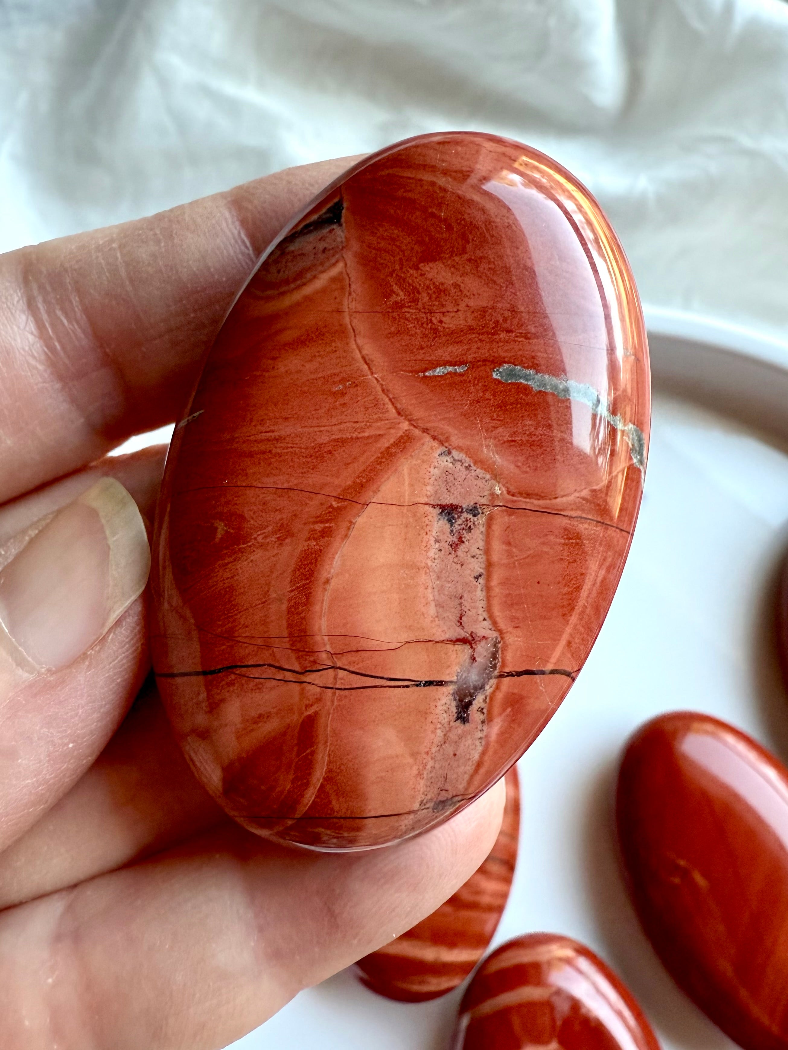 Close-up of Red Jasper palm stone — deep red tones with natural veining and unique mineral patterns.