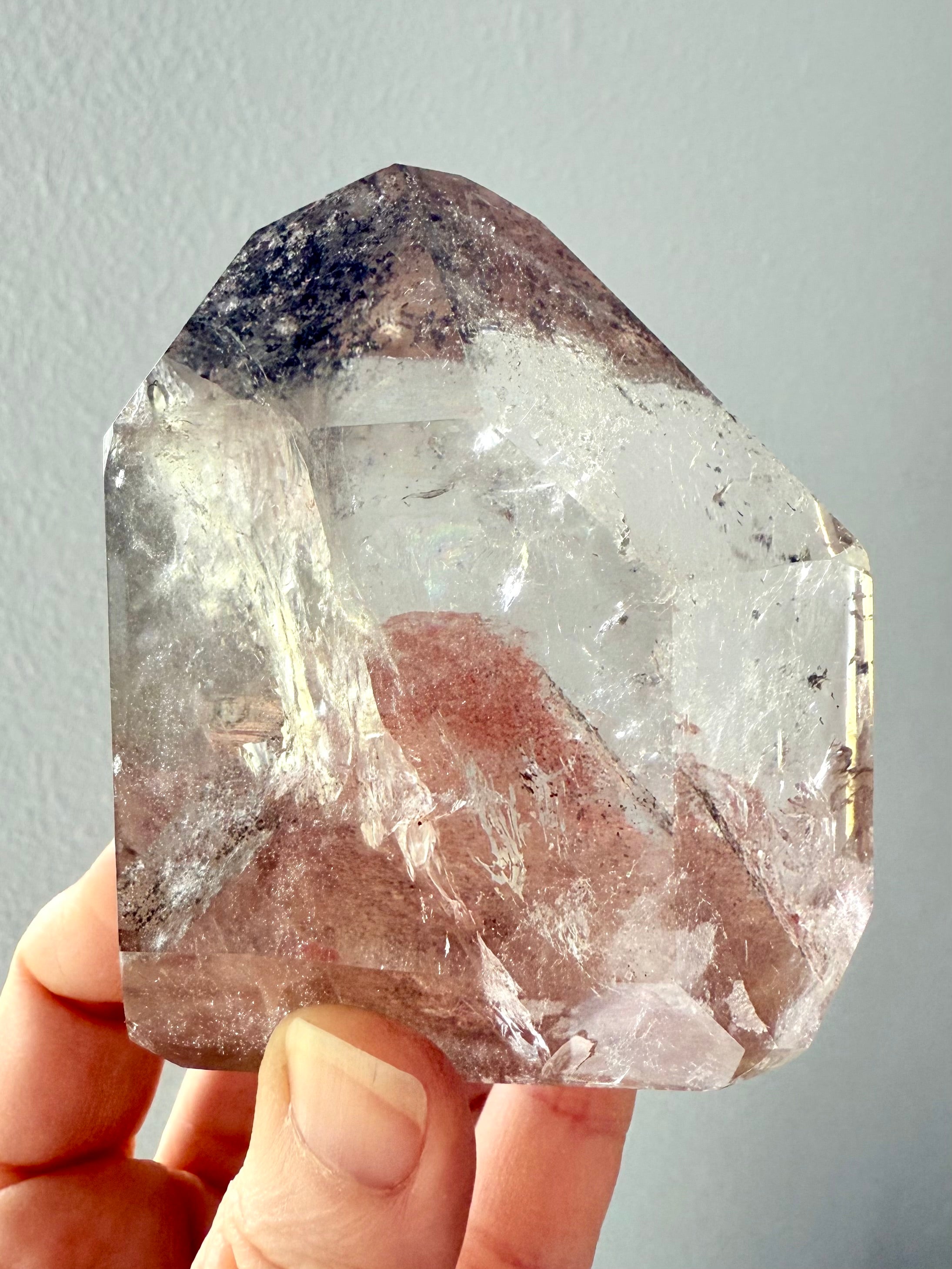 This Lodolite Garden Quartz Tower held to the light to show the big reddish orange phantom pyramid