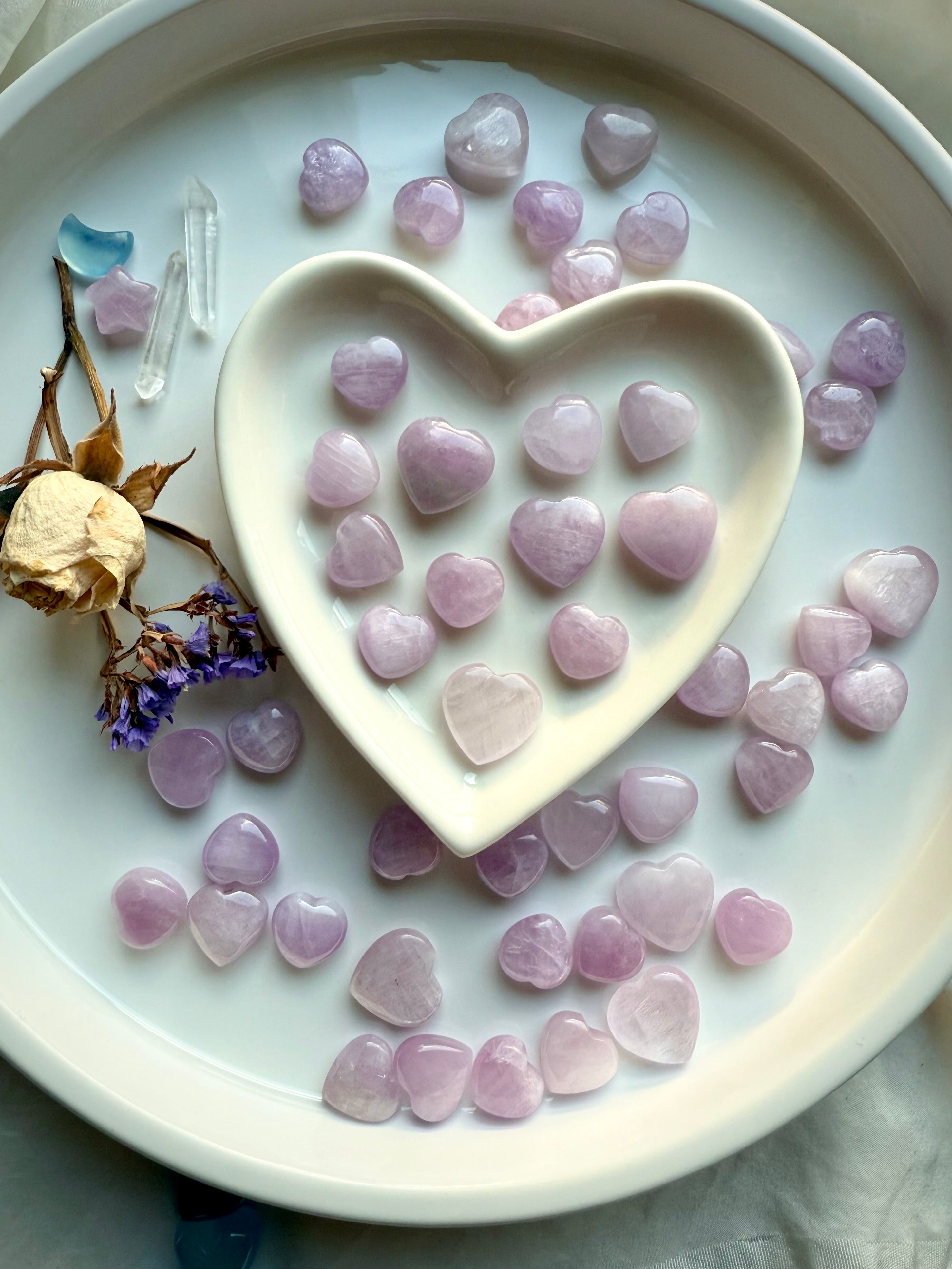 Mini Kunzite Hearts displayed in a heart dish with dried flowers and clear quartz – pink crystal hearts for love, compassion and gentle healing energy