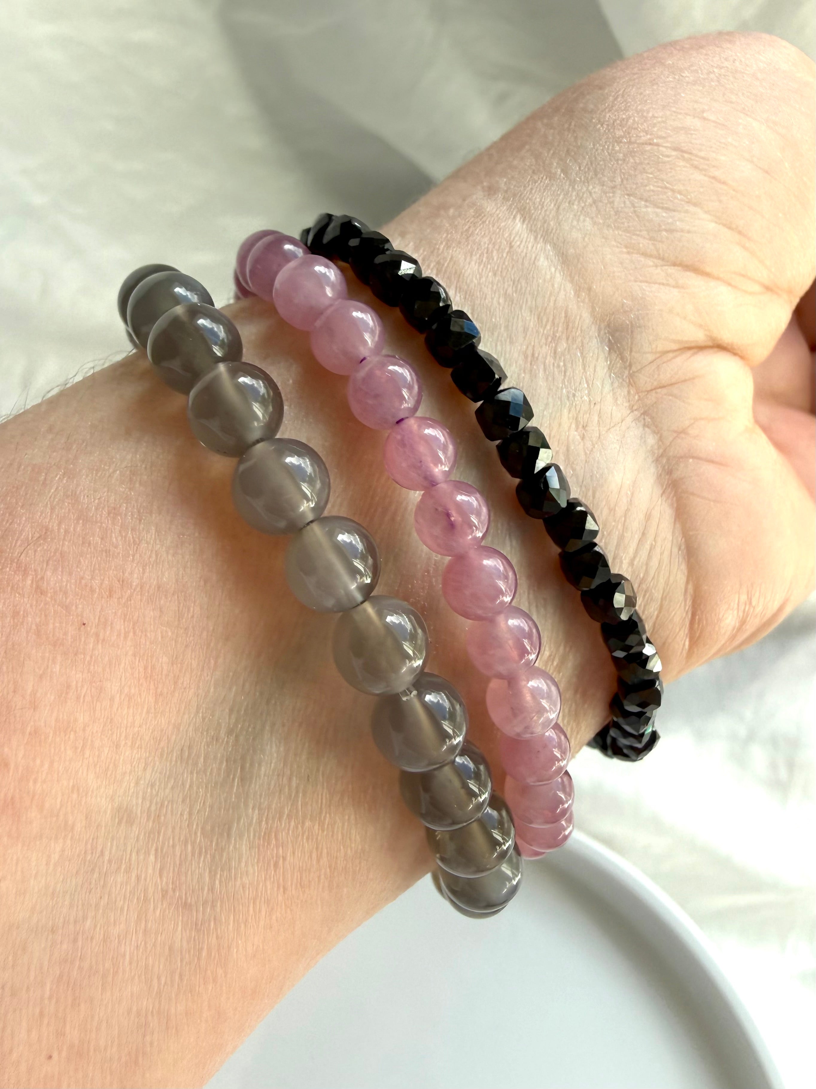Crystal bracelet stack featuring Lavender Rose Quartz, Black Moonstone, and faceted Black Spinel gemstone bracelets