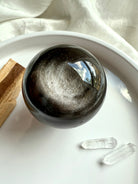 Altar display of Silver Sheen Obsidian sphere showing metallic silver sheen and swirling energy patterns