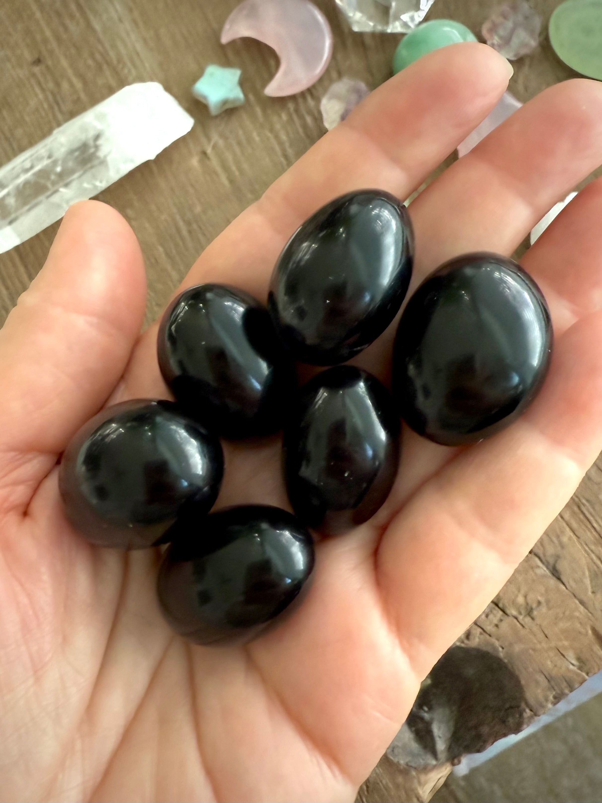 Tumbled Black Obsidian shown on my hand for scale, photographed in natural light