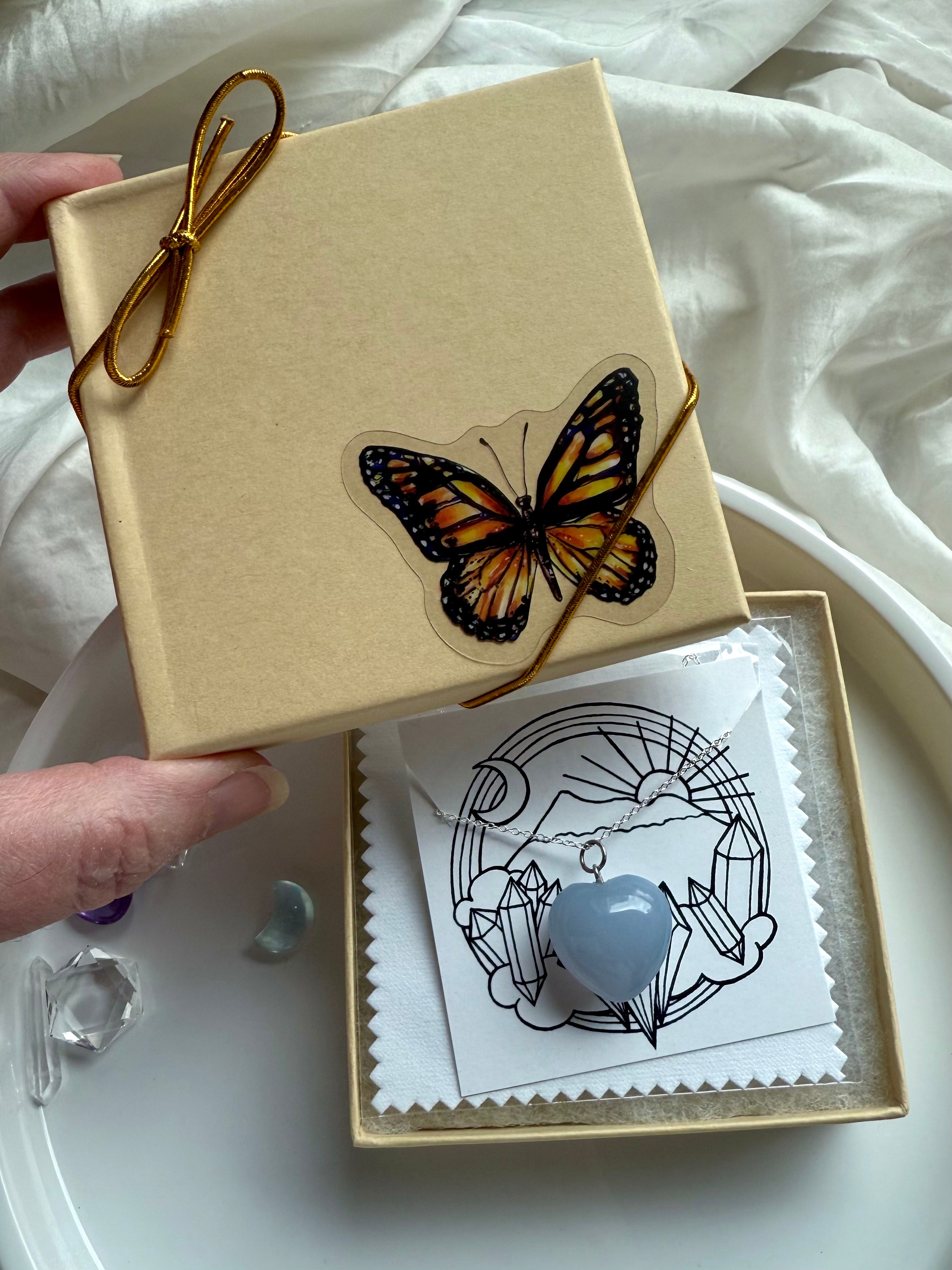 Gift-ready Blue Chalcedony heart pendant necklace in butterfly box with gold cord and crystal-themed packaging.