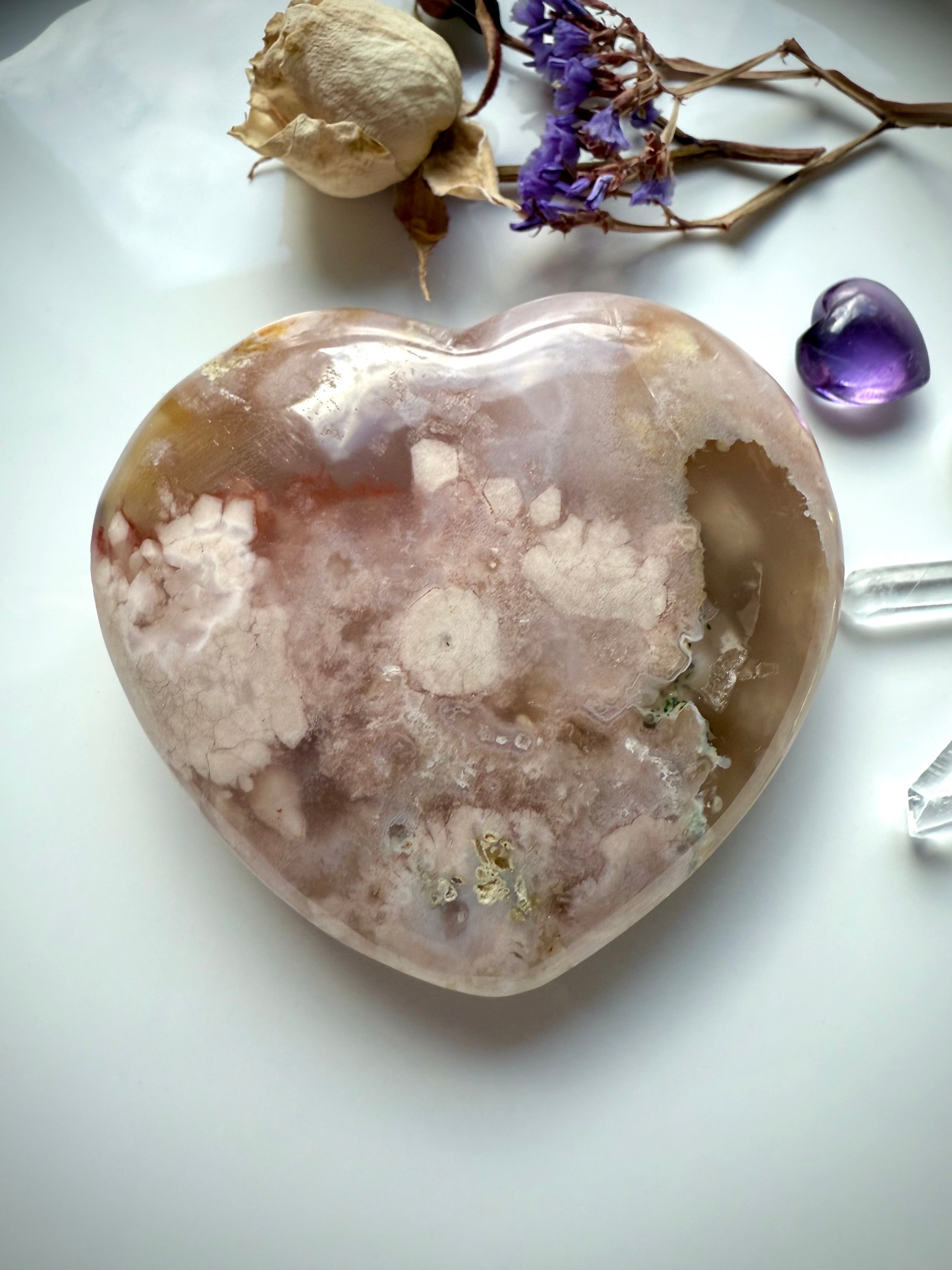 Flatlay pink crystal heart with dried roses, amethyst, and quartz points for sacred altar vibes
