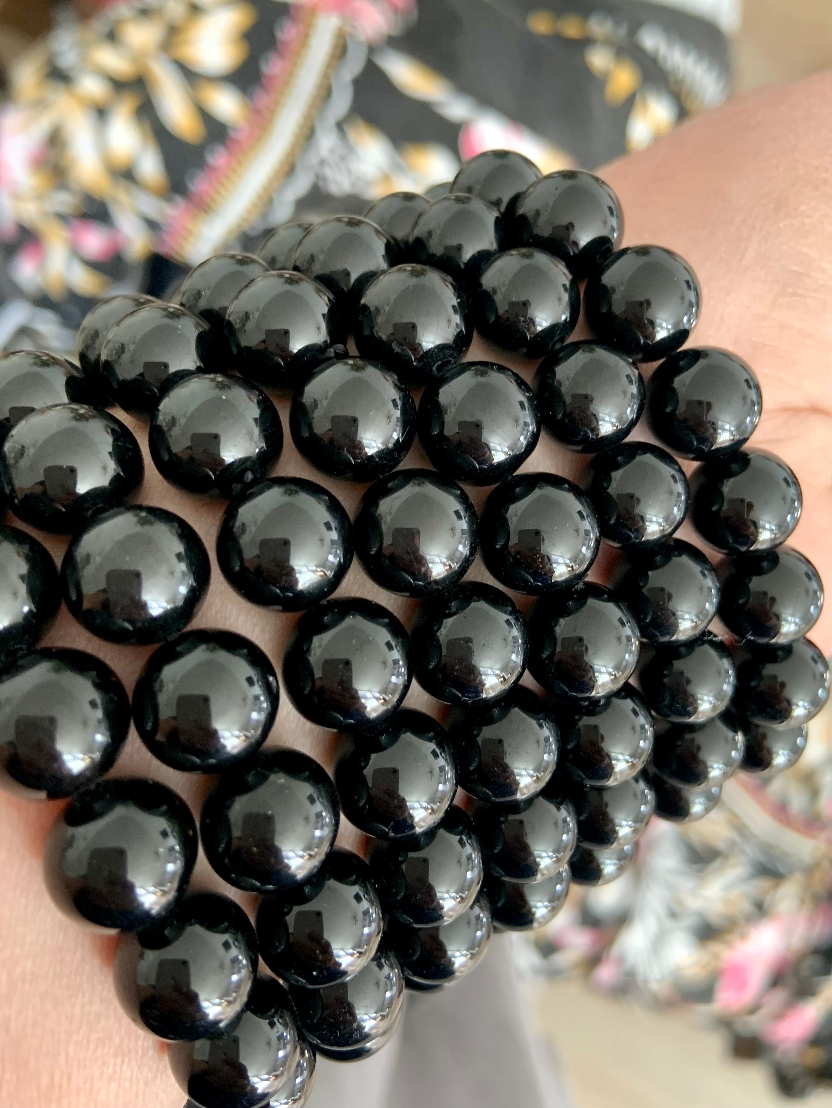 Angled closeup of stacked glossy Black Tourmaline bracelets — natural black crystal beads for protection, clearing, and grounding