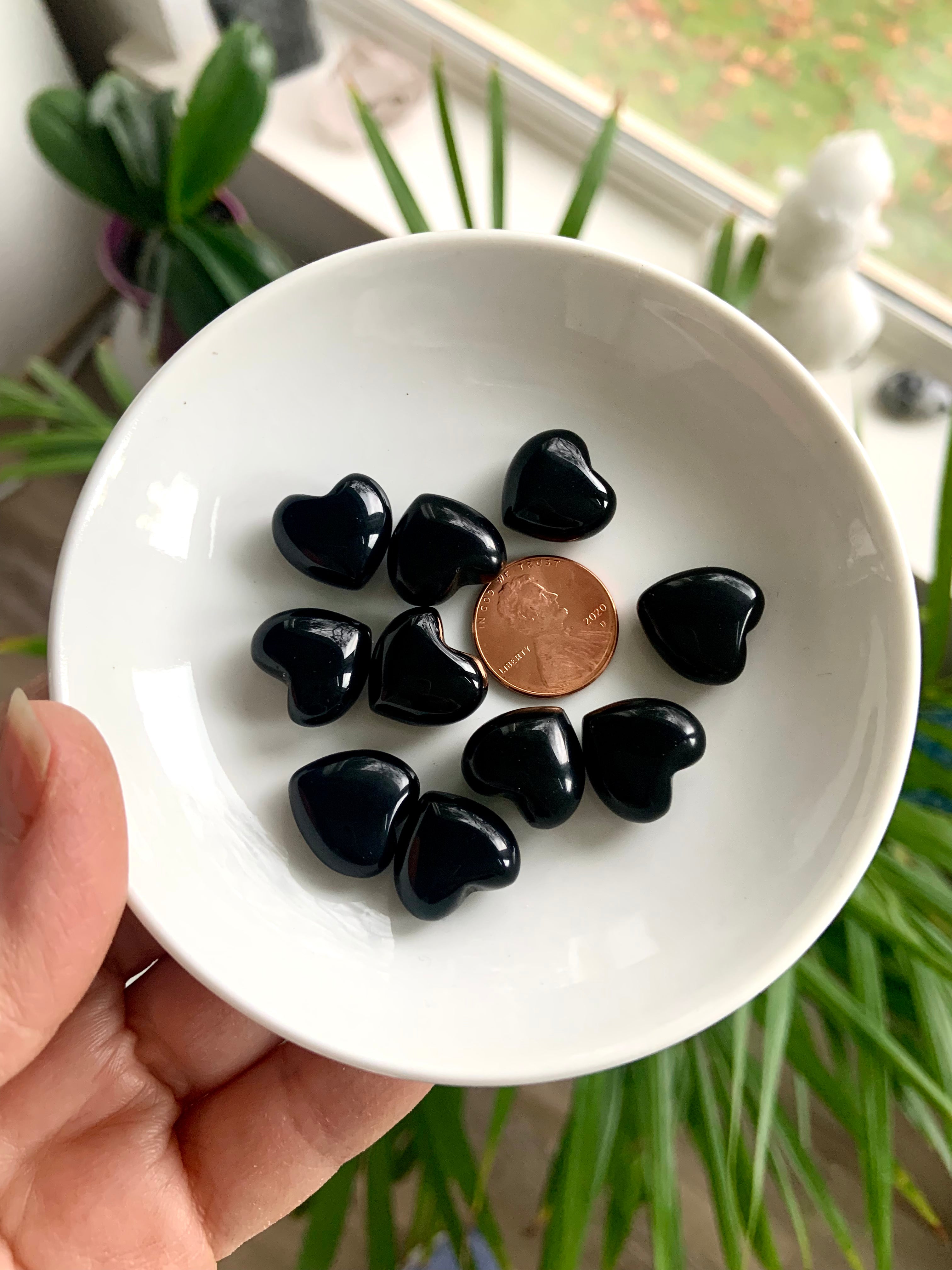 Our mini sized Black Obsidian Hearts shown on a white plate with a penny for scale