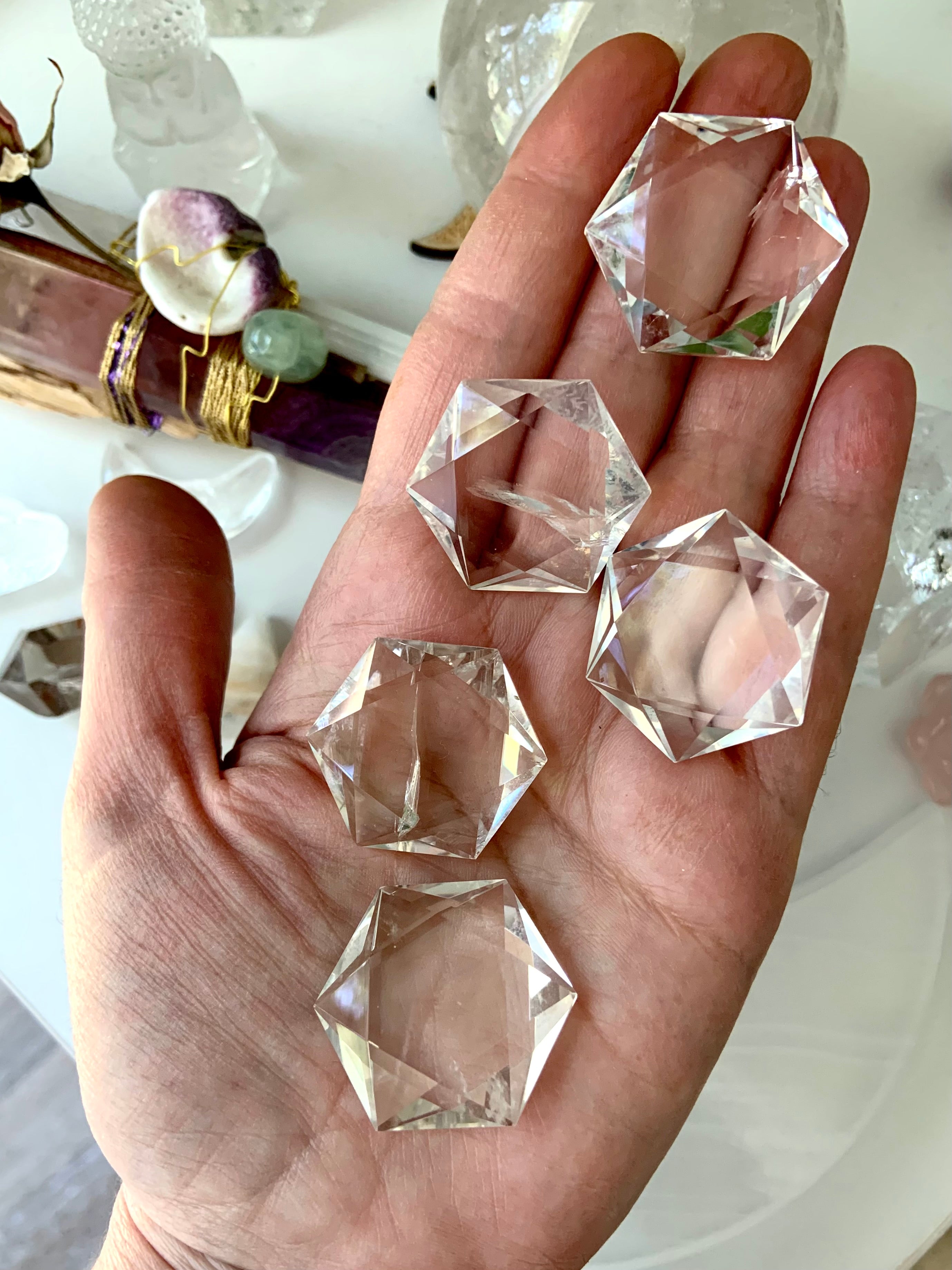 Array of faceted Clear Quartz hexagon crystals displayed on hand, sparkling with prismatic clarity