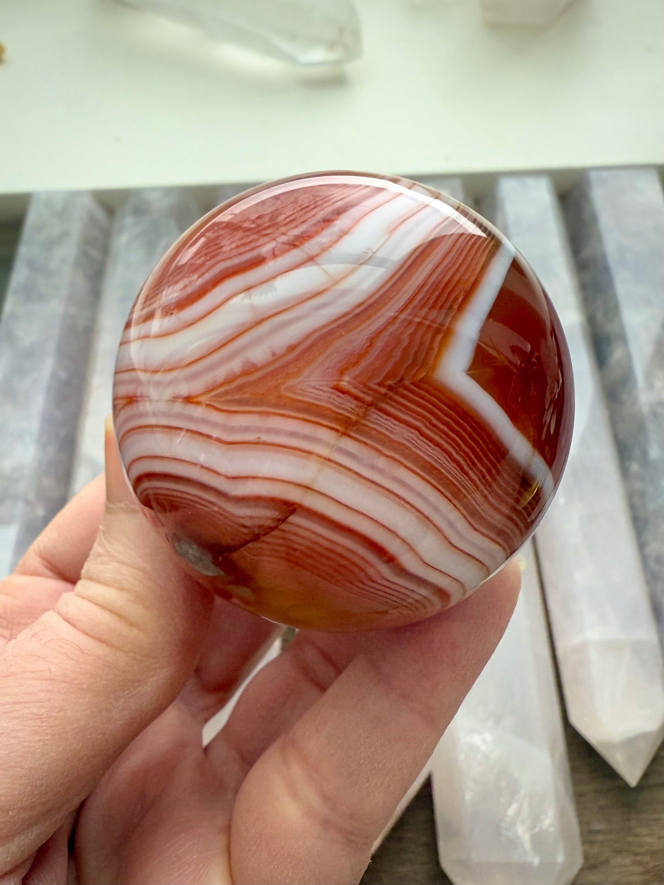 A stunning banded carnelian sphere with an intricate chevron pattern
