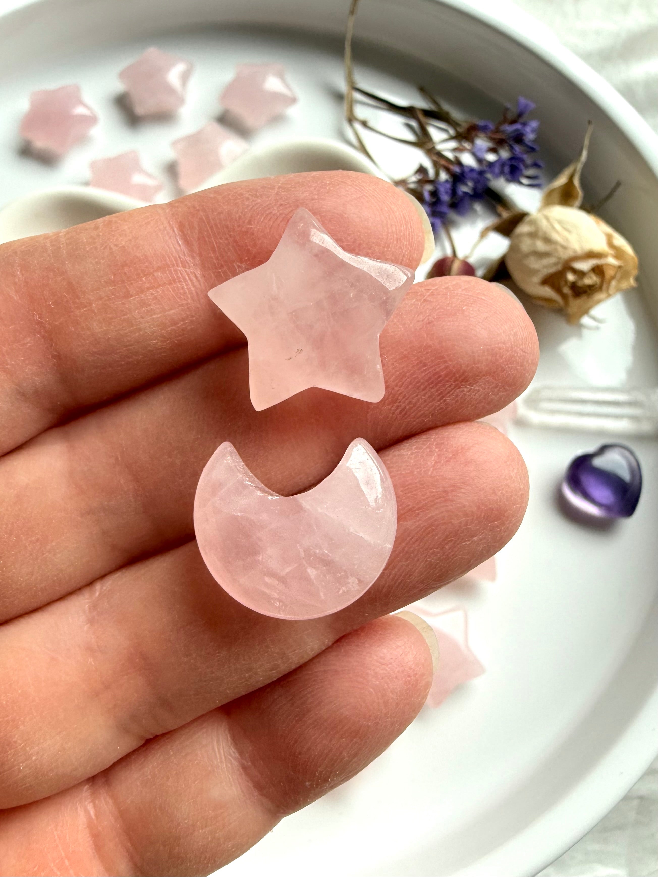 Closeup of Rose Quartz mini moon and star carvings on hand. Petite Heart Chakra carvings radiating unconditional love, peace &amp; gentle emotional support.