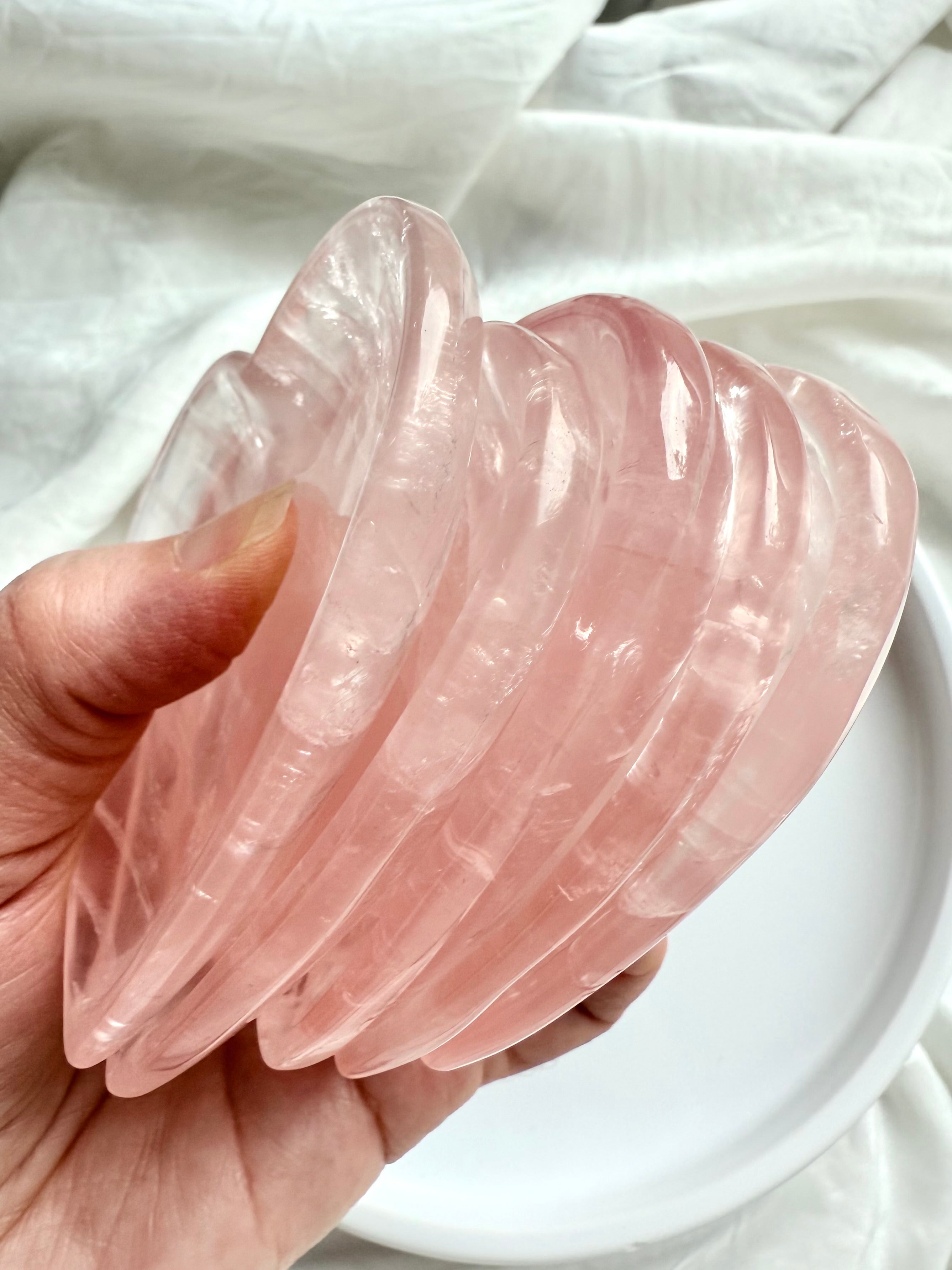 Multiple Rose Quartz heart bowls stacked together in hand, highlighting their clarity and feminine pink crystal energy.