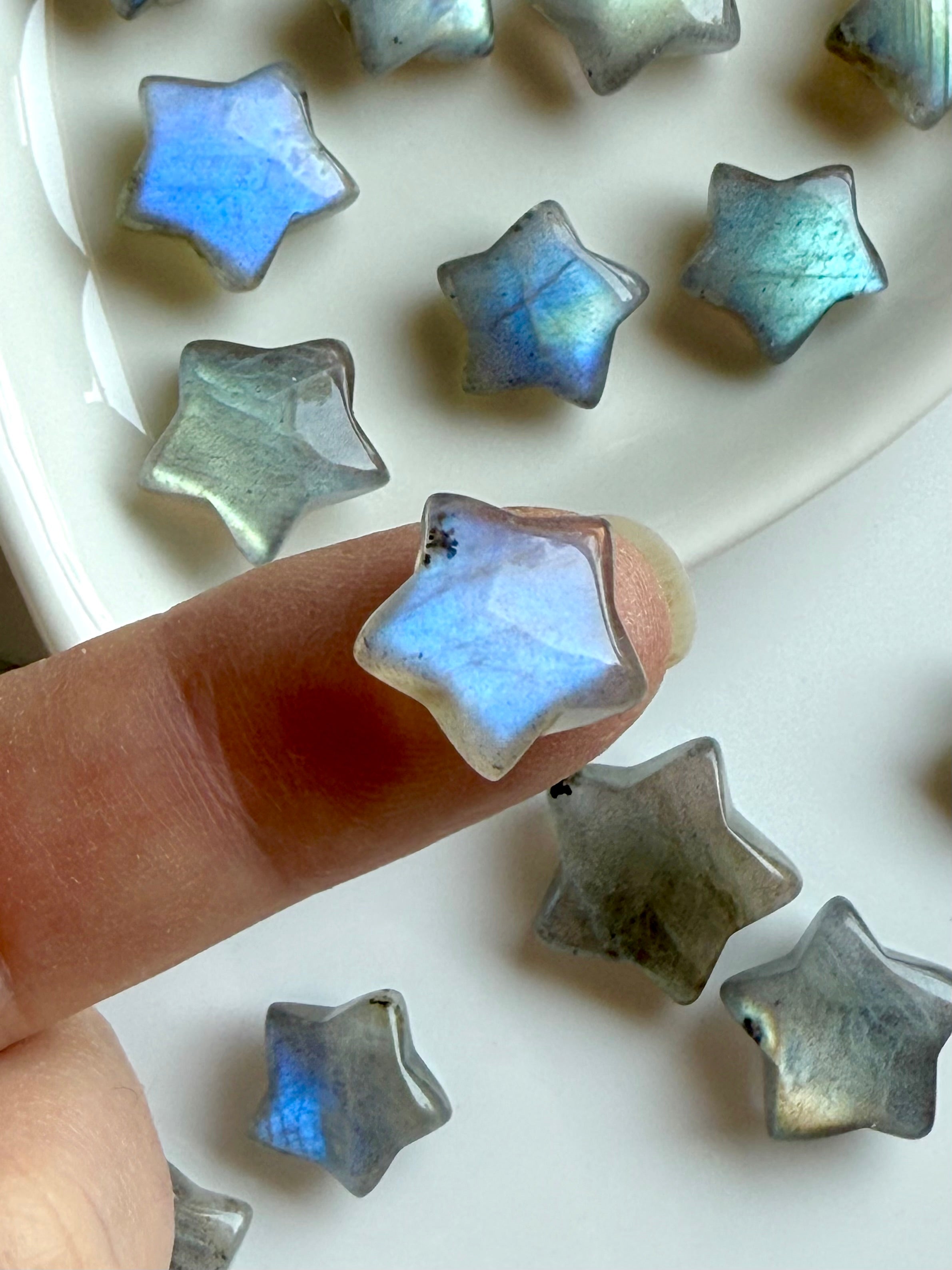 Pastel Labradorite mini star shown on a fingertip for scale — soft crystal carving with rainbow flash for intuitive insight &amp; healing energy.