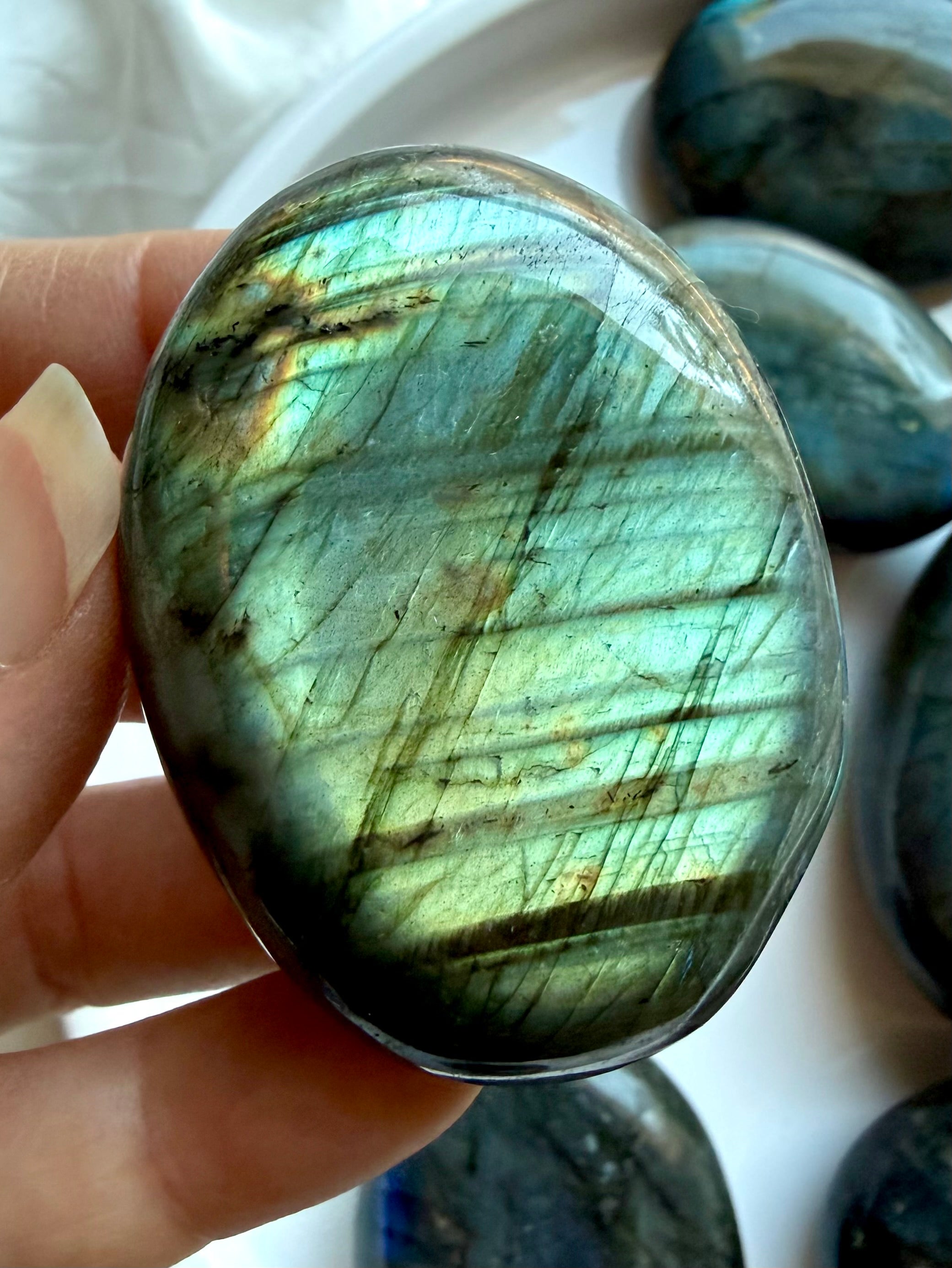 Green flash Labradorite palm stone held in hand with natural iridescence and polished crystal surface