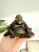 Golden Sheen Obsidian Buddha carving with joyful expression held in hand, crystal statue for protection, abundance, and light energy