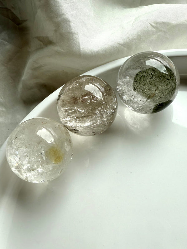 three garden quartz spheres on a white plate – lodolite spheres for spiritual healing