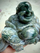 Three-quarter view of a Large Moss Agate Laughing Buddha crystal statue with polished finish