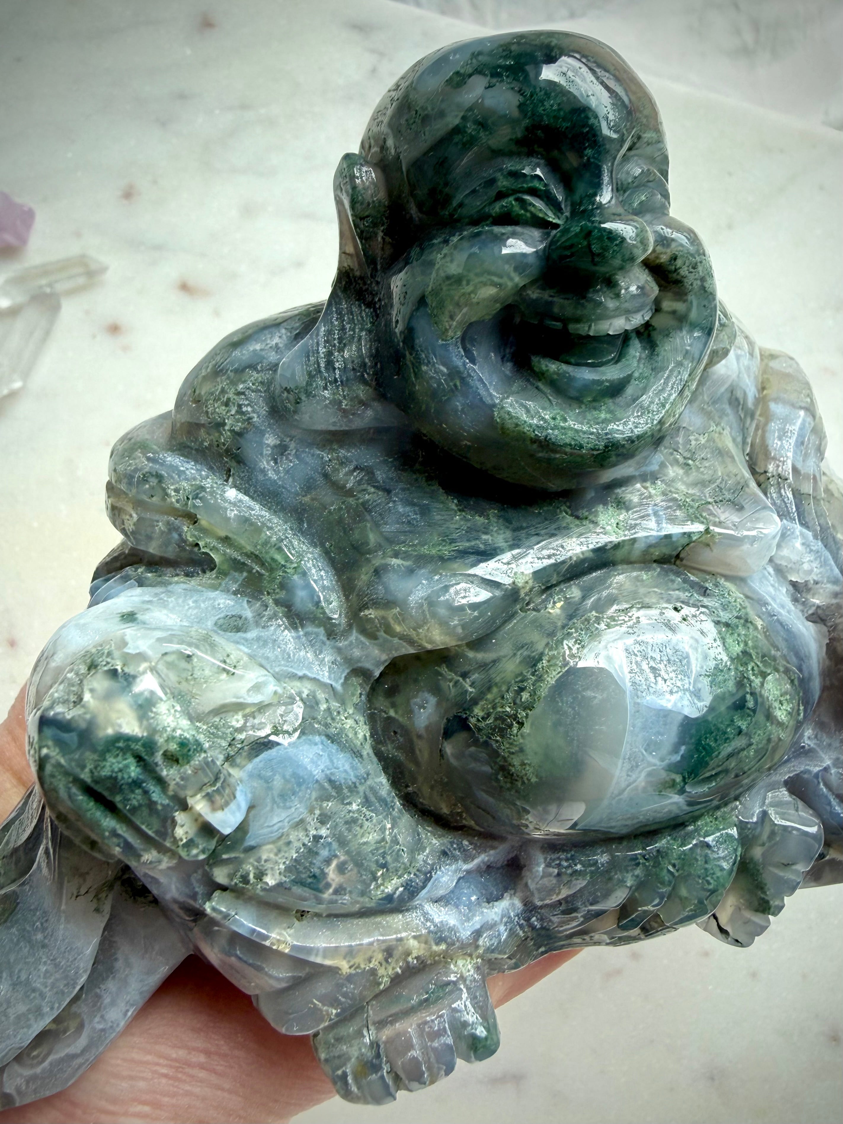 Three-quarter view of a Large Moss Agate Laughing Buddha crystal statue with polished finish