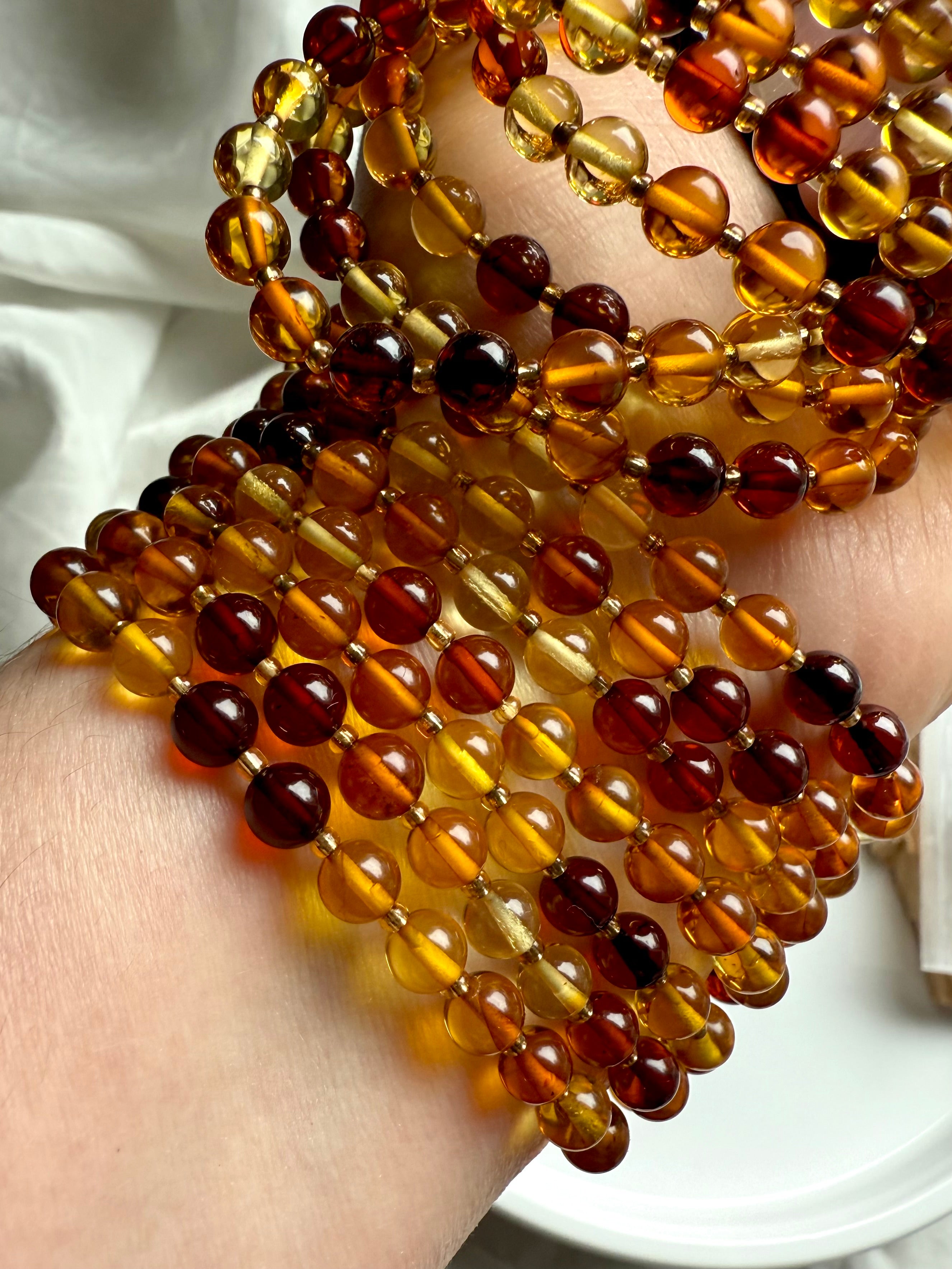 Layered amber beaded bracelets glowing with warmth + light – natural amber crystal for energy, confidence + joy