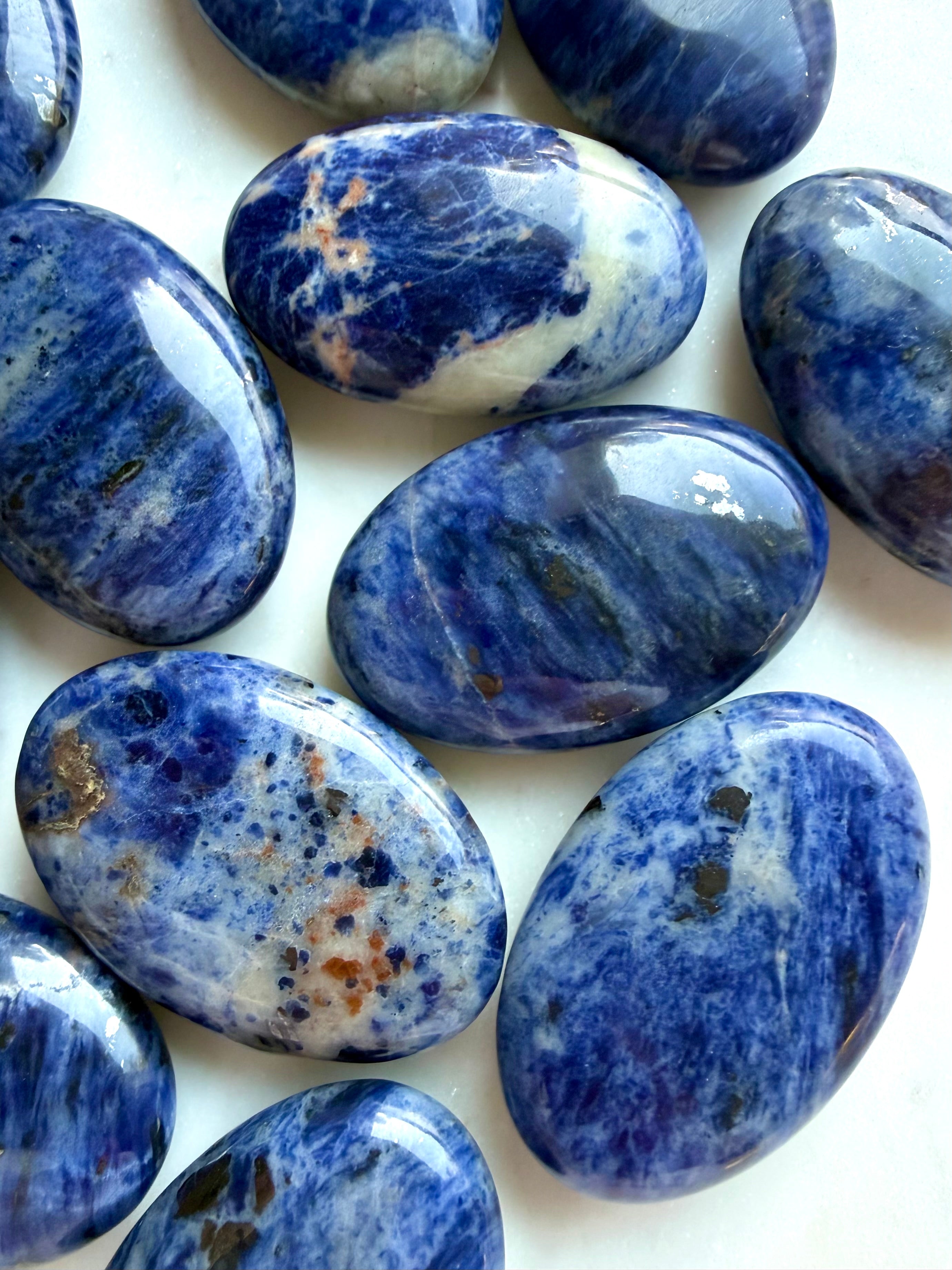 Close up of blue Sodalite palm stones with cobalt tones, white veining & varied mineral inclusions