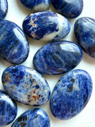 Close up of blue Sodalite palm stones with cobalt tones, white veining & varied mineral inclusions