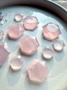 Several sizes of faceted rose quartz crystal hexagons on white, Heart Chakra crystals with natural veining & soft pink color