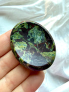 Close-up of Dragon Blood Stone crystal worry stone with dramatic forest-green and burgundy patterns for courage and emotional strength