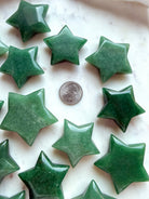 Green Aventurine crystal stars shown with a US Quarter for scale, showing natural color variation